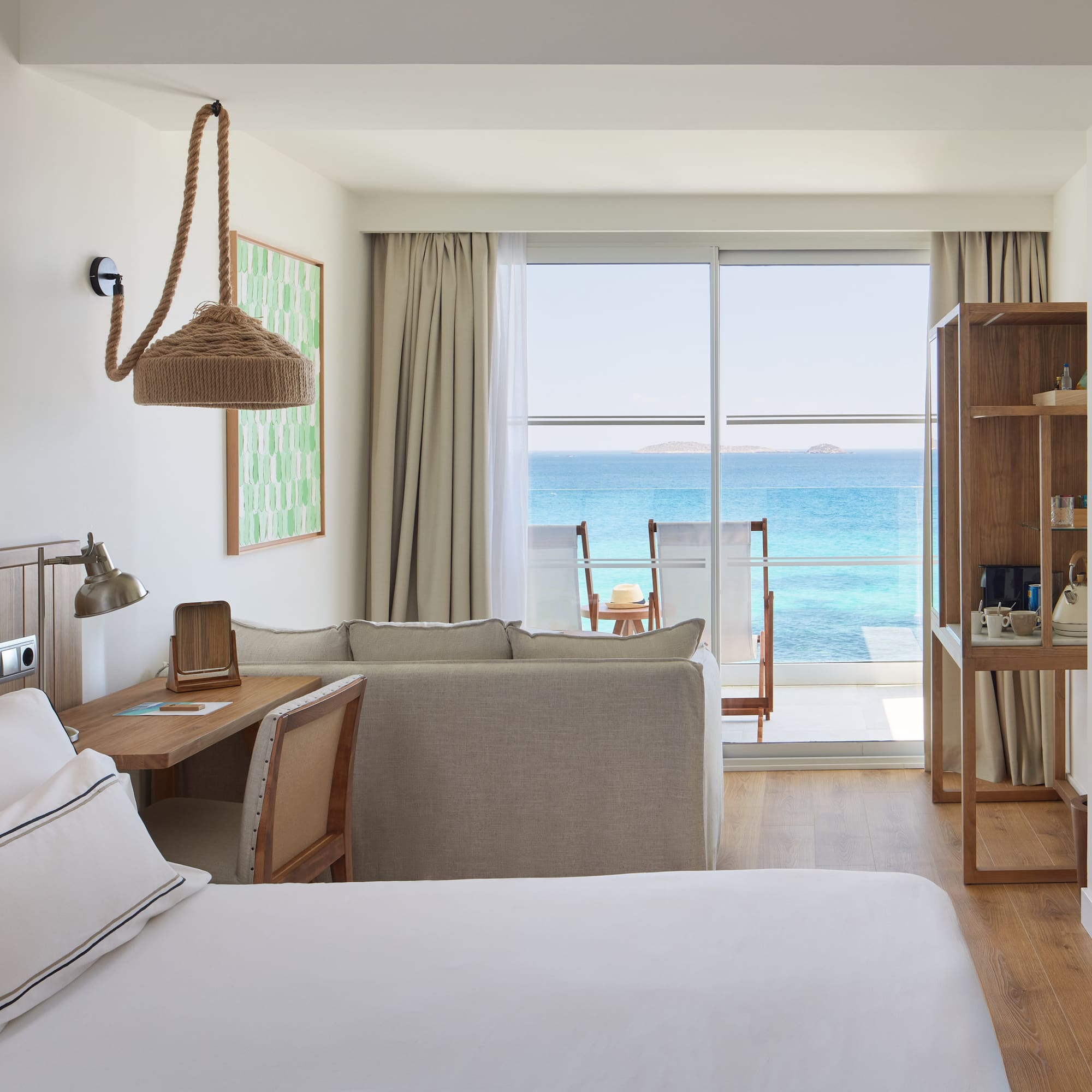 Modern resort room with ocean view balcony, bed, and sofa.