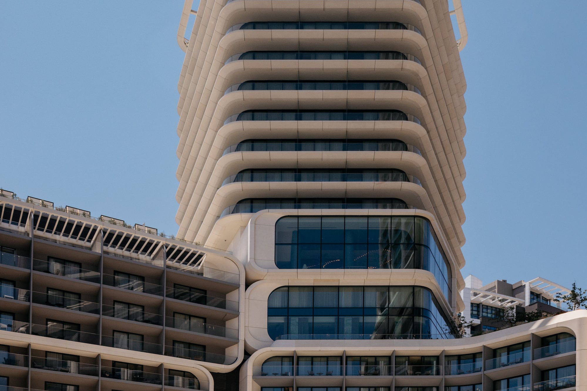 Contemporary hotel building with unique curved white balconies and glass.