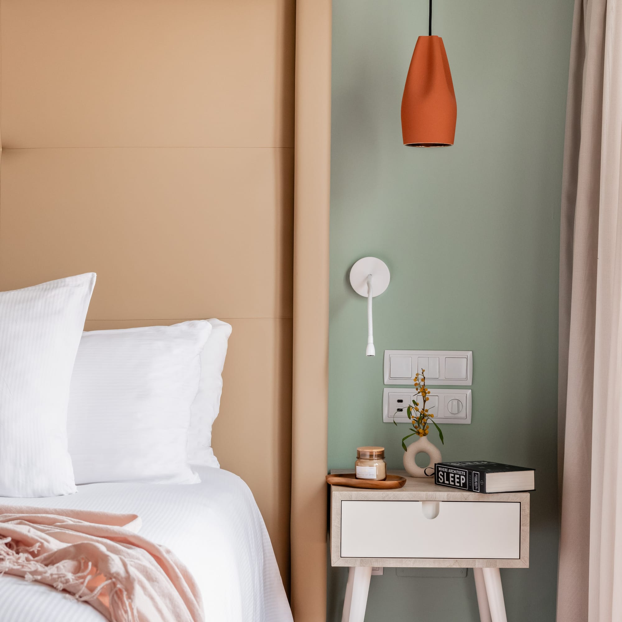 a bed with a pink blanket and a small end table