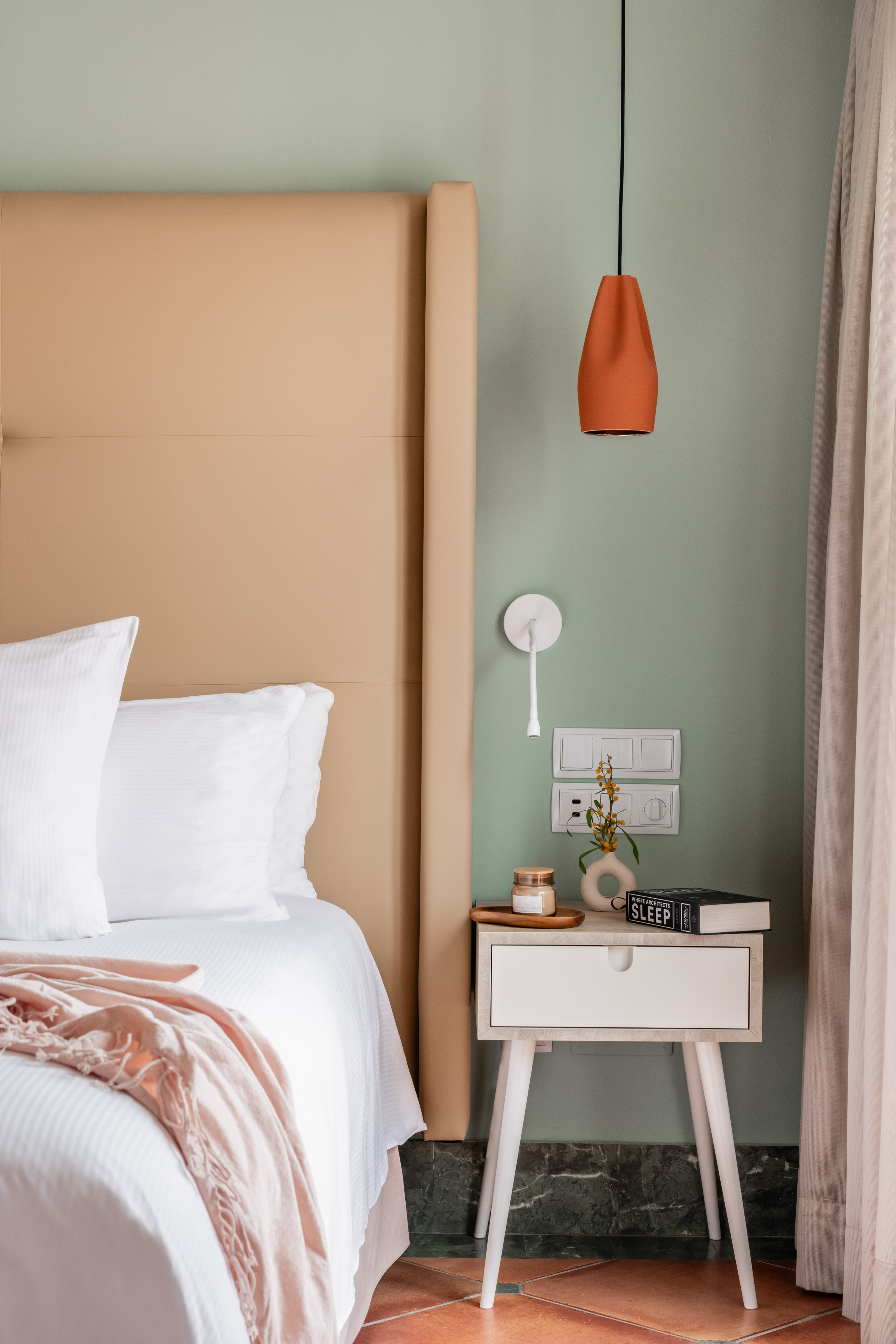 a bed with a pink blanket and a small end table