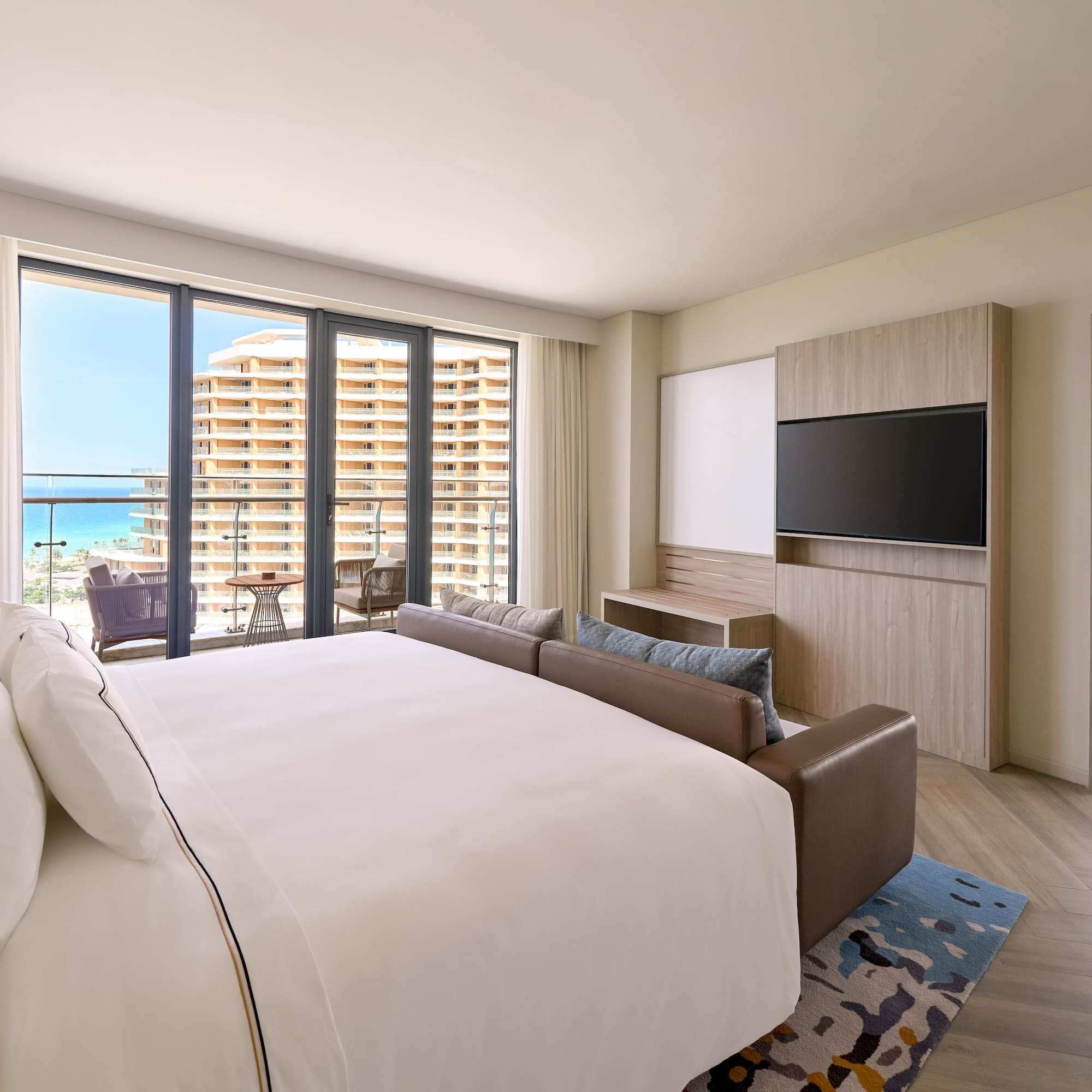 Luxury ocean view hotel suite with king bed and balcony.