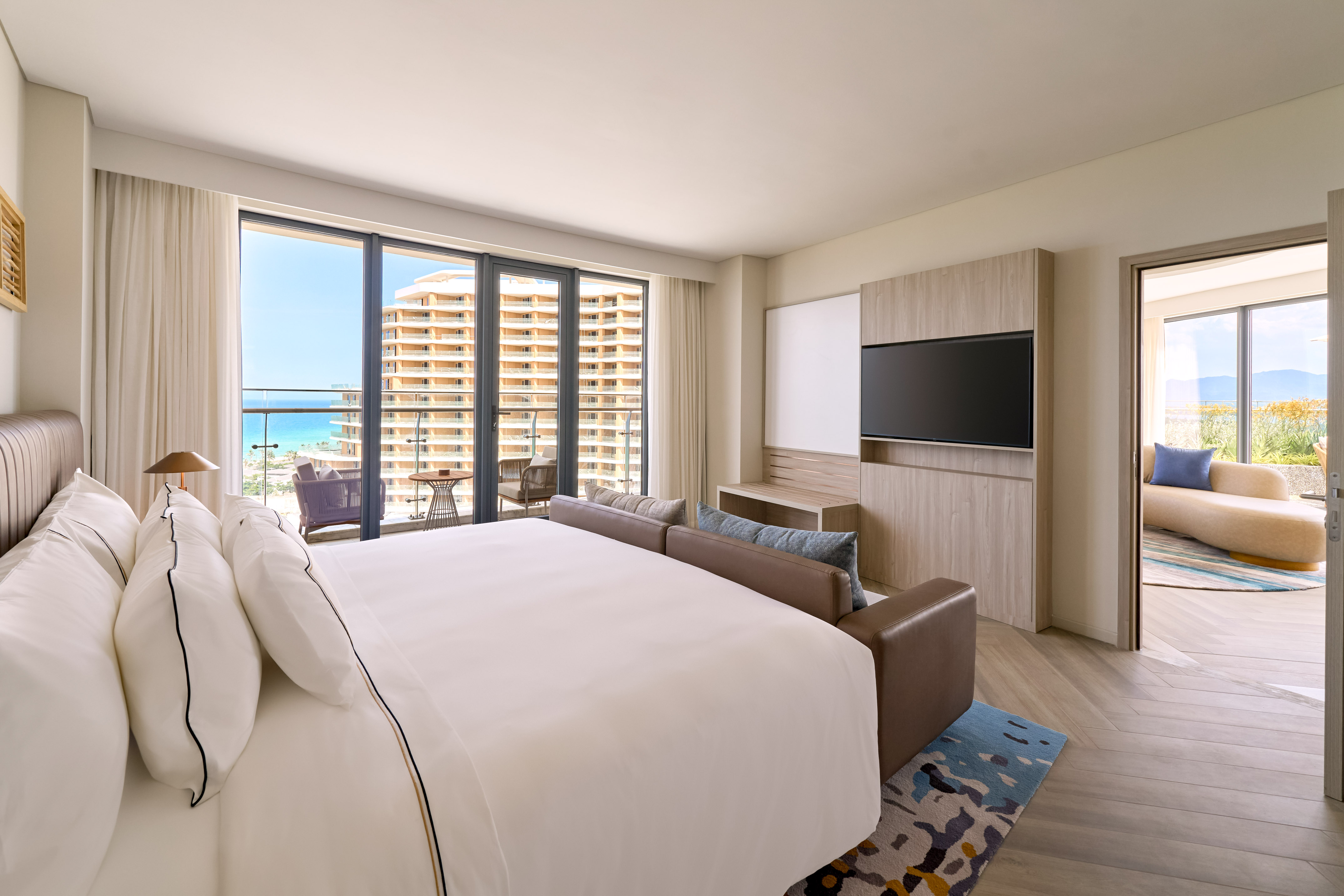 Luxury ocean view hotel suite with king bed and balcony.