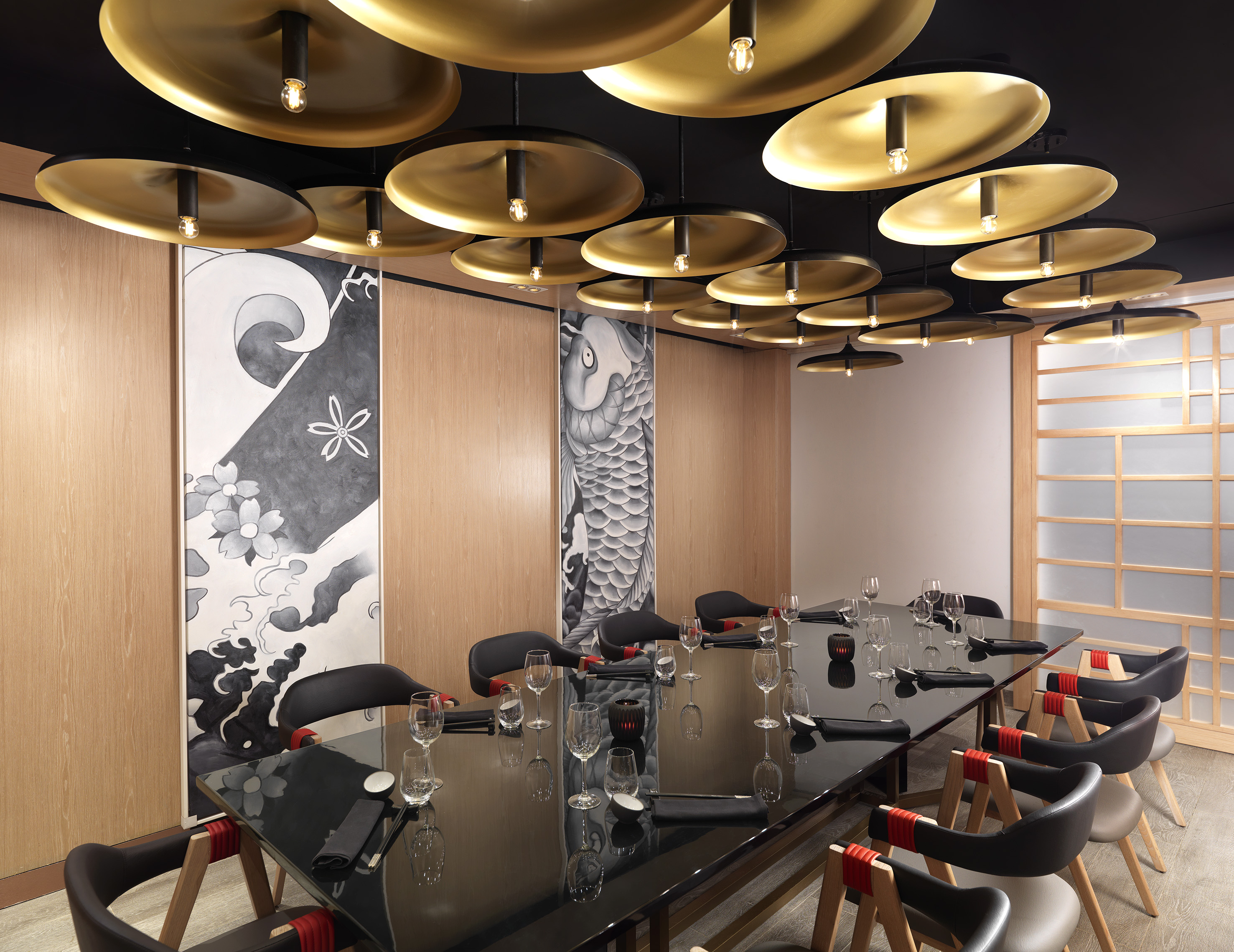 Elegant Japanese private dining room with gold ceiling lights, black table, and koi mural.