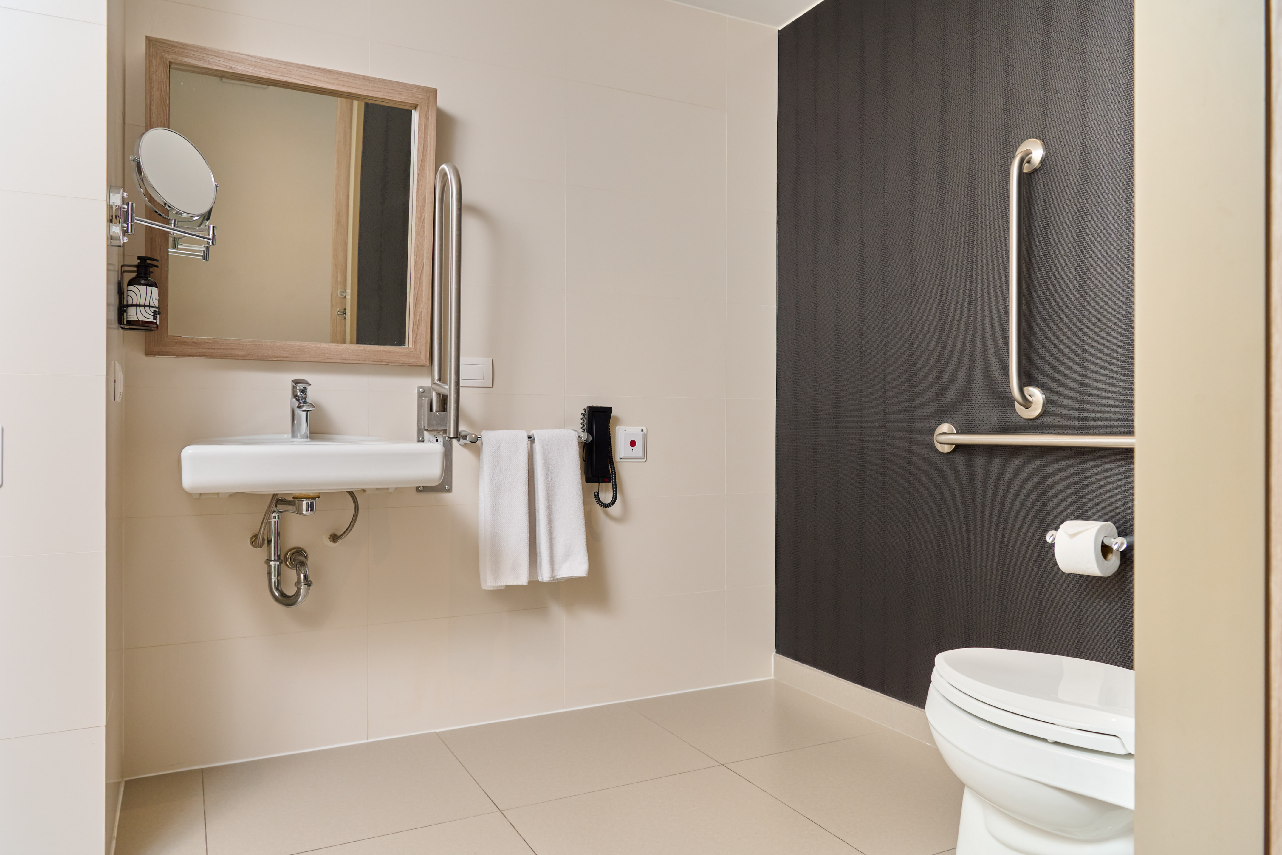 Accessible bathroom with grab bars, ADA sink, toilet, emergency call.