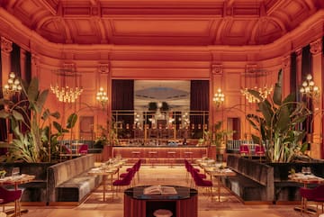 a room with tables and chairs and chandeliers