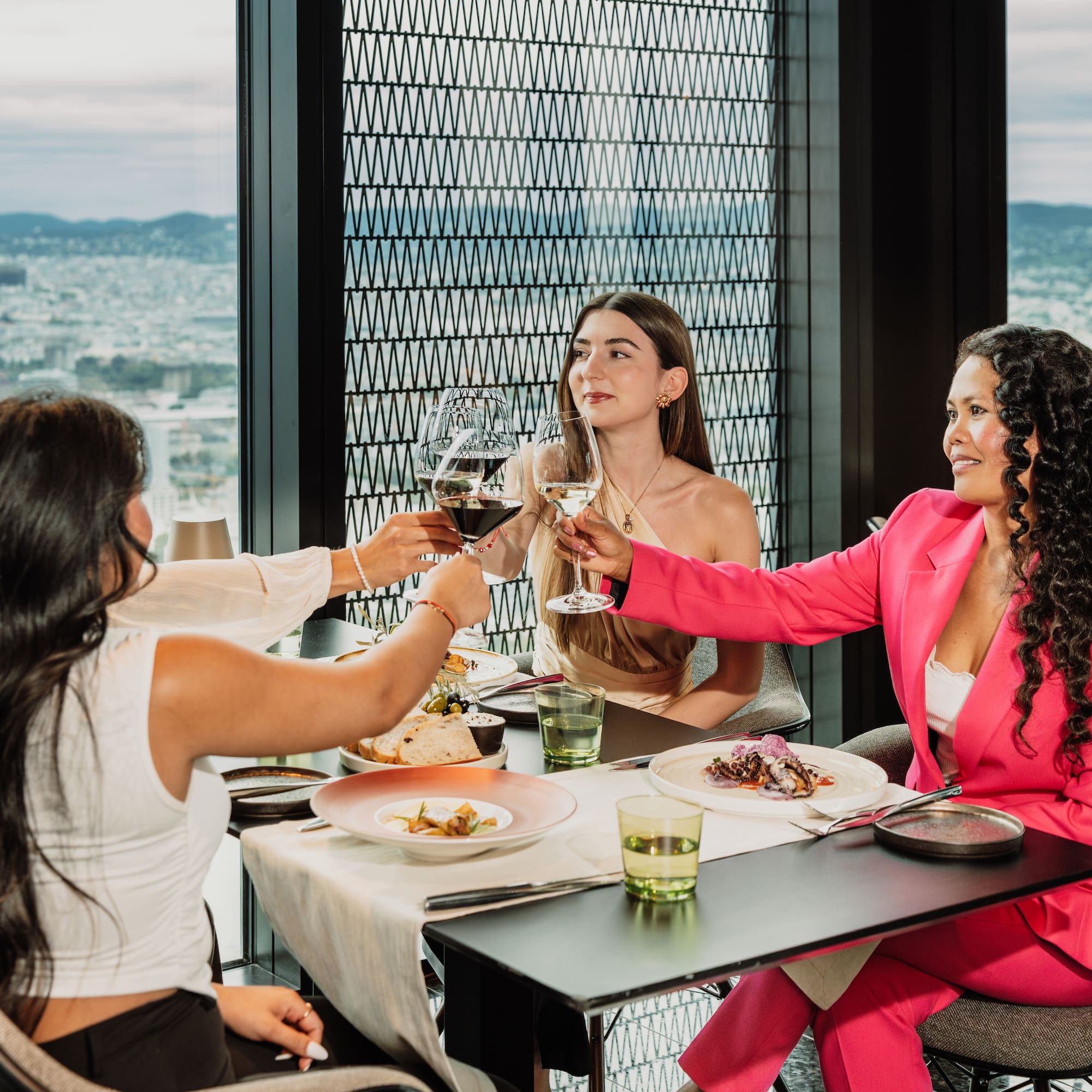 a group of women sitting at a table clinking glasses