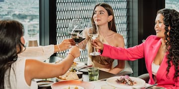 a group of women sitting at a table clinking glasses