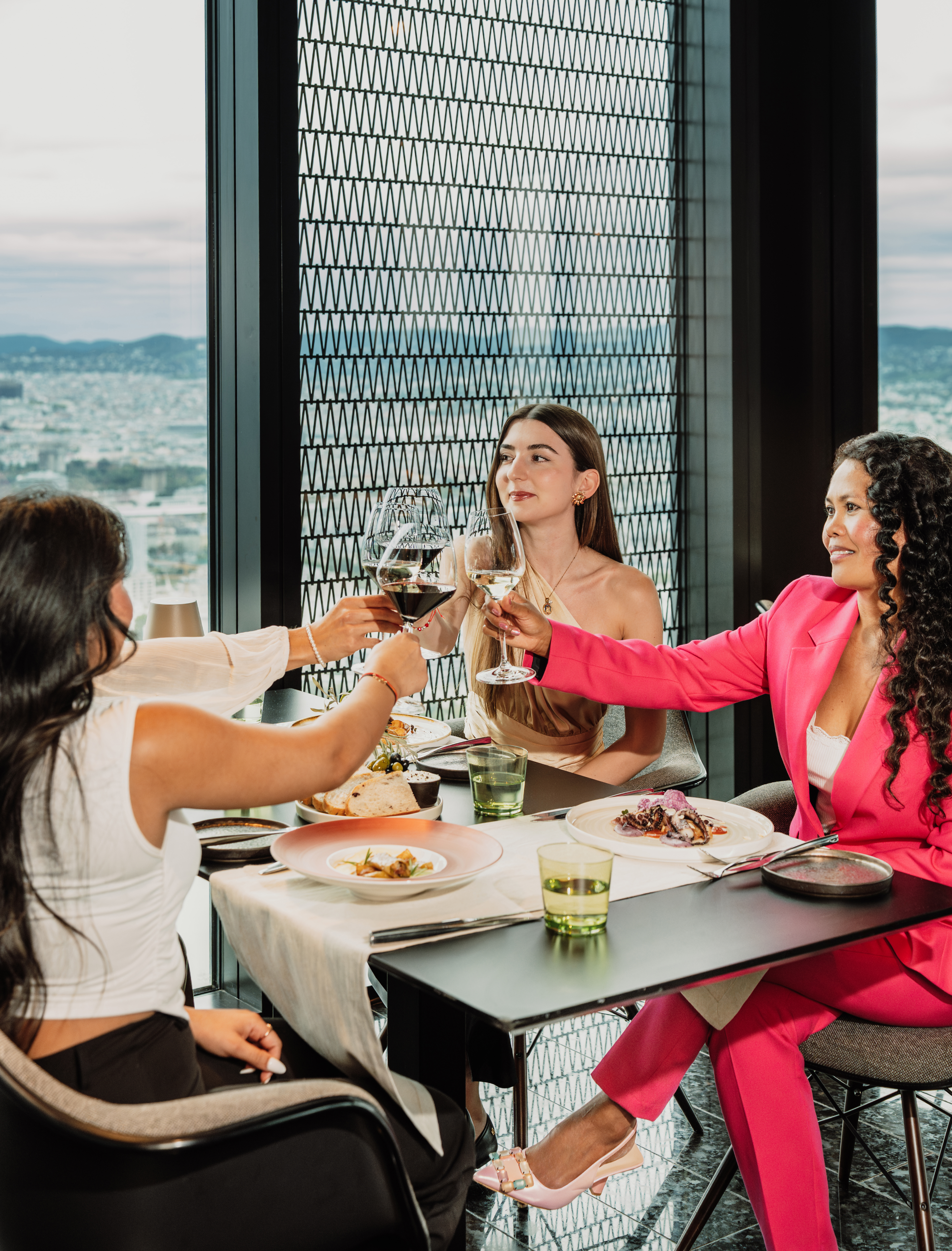 a group of women sitting at a table clinking glasses