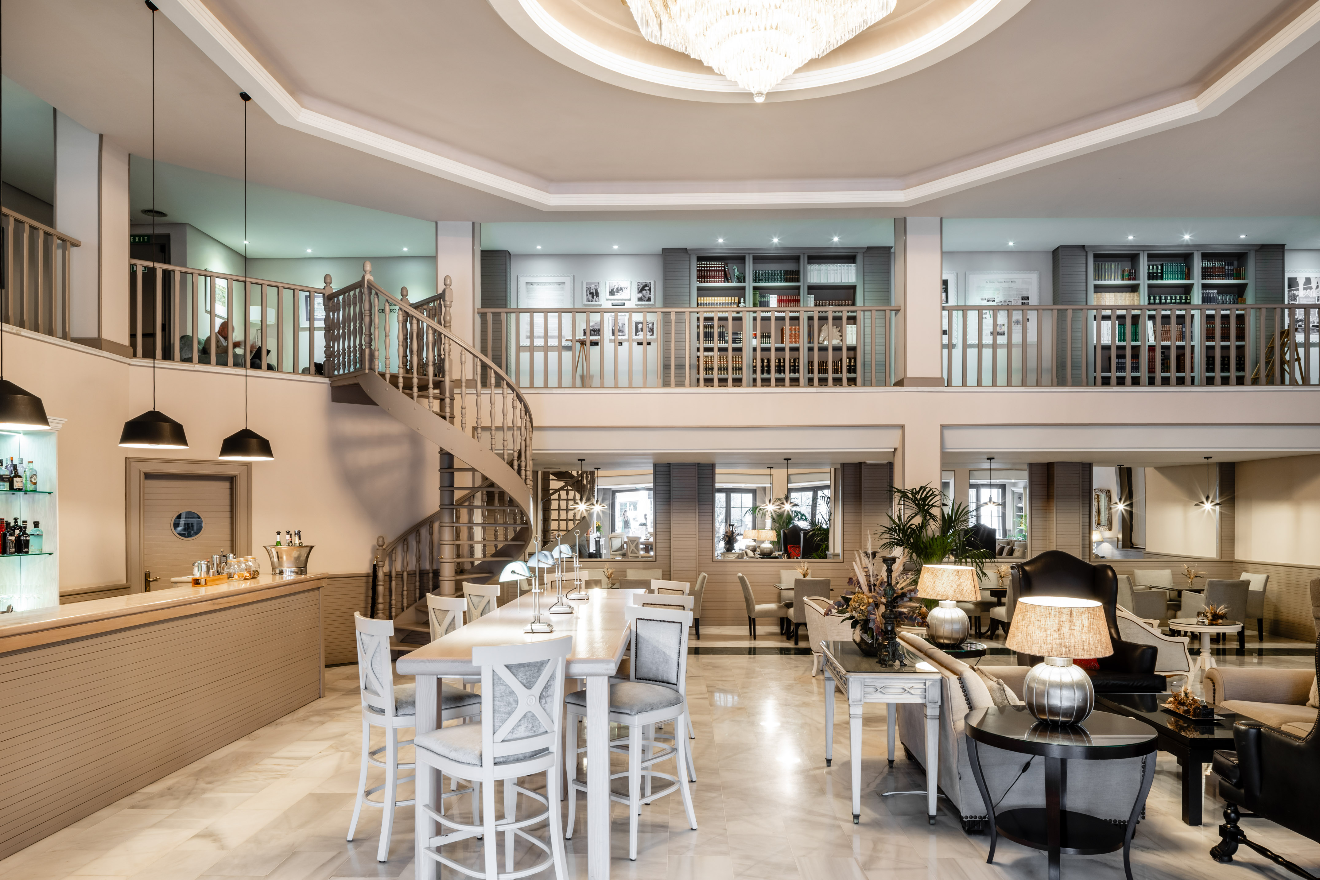 Elegant hotel lobby with spiral staircase, bar, and luxurious lounge seating.