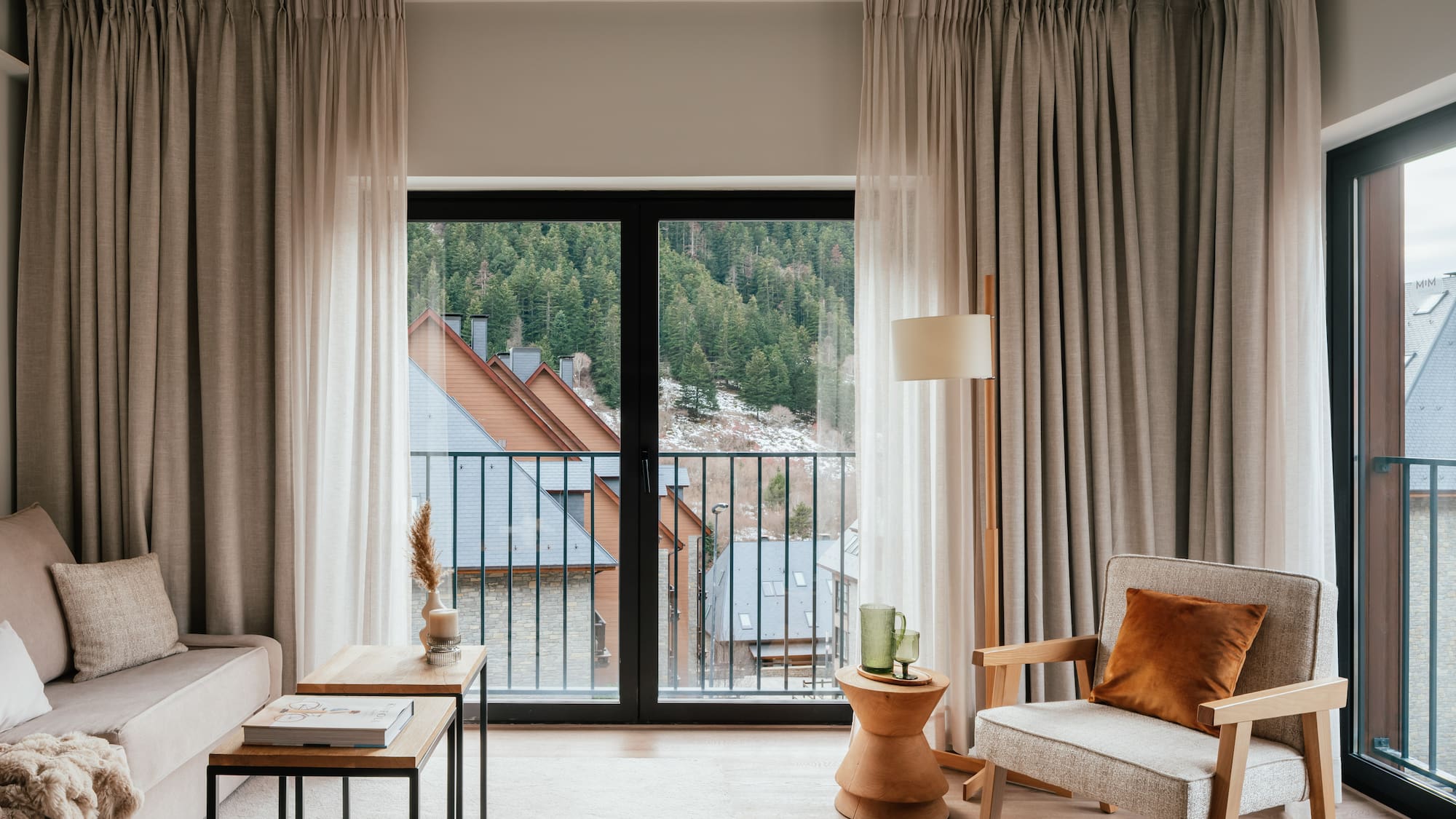 Modern apartment living room with balcony view of mountain forest village.