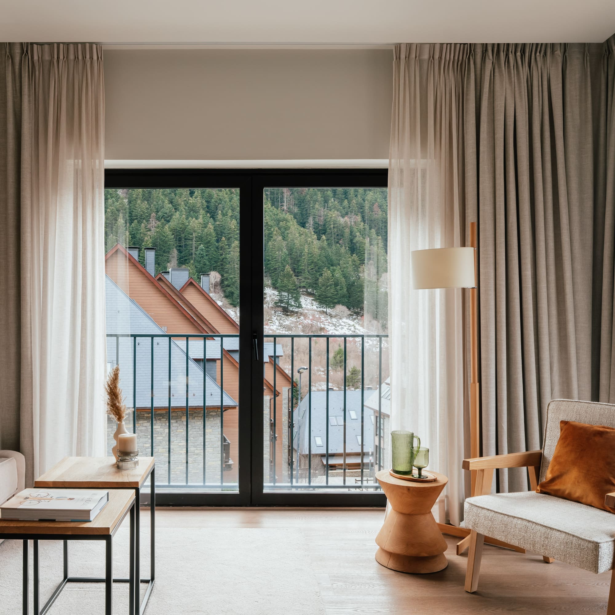 Modern apartment living room with balcony view of mountain forest village.