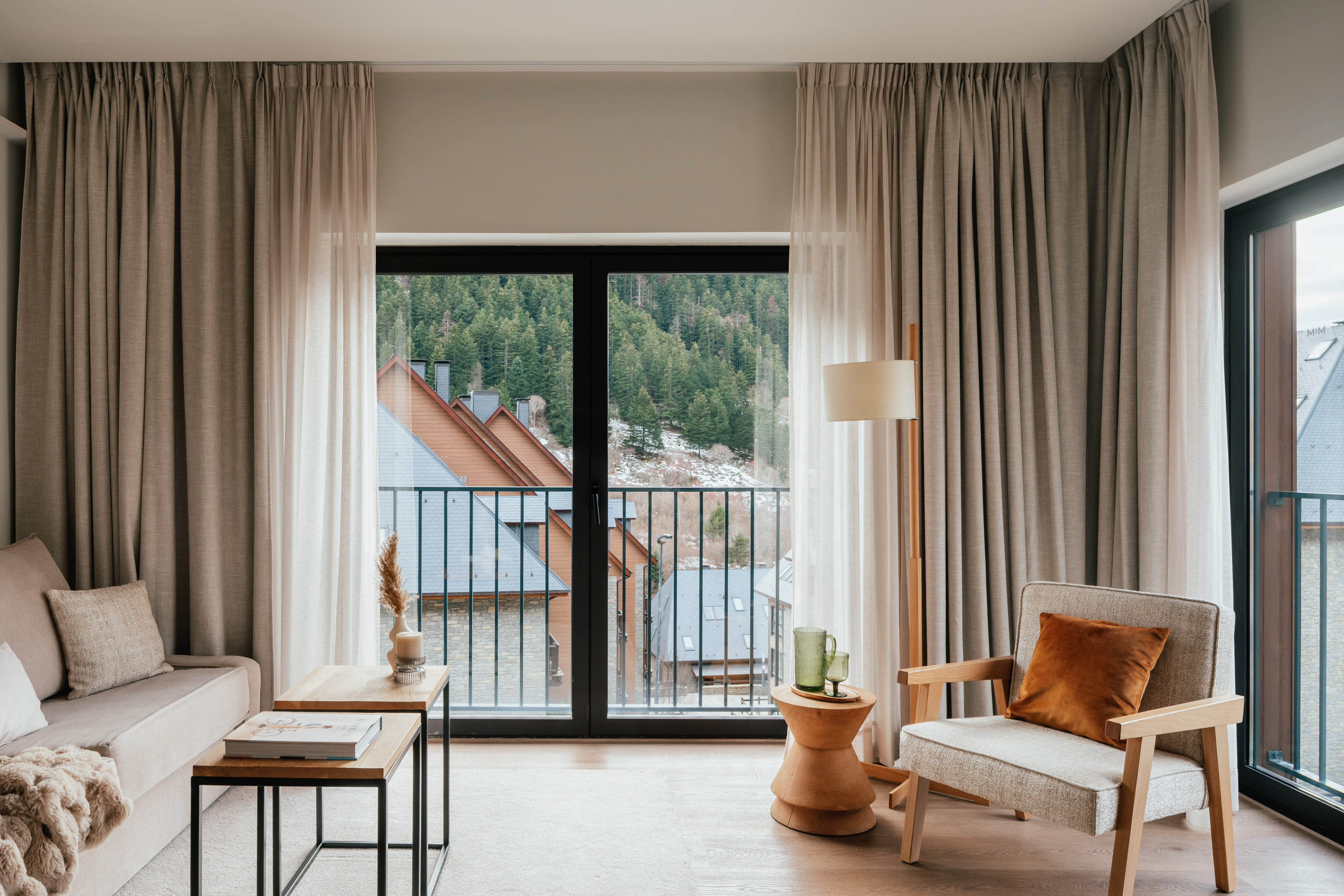 Modern apartment living room with balcony view of mountain forest village.