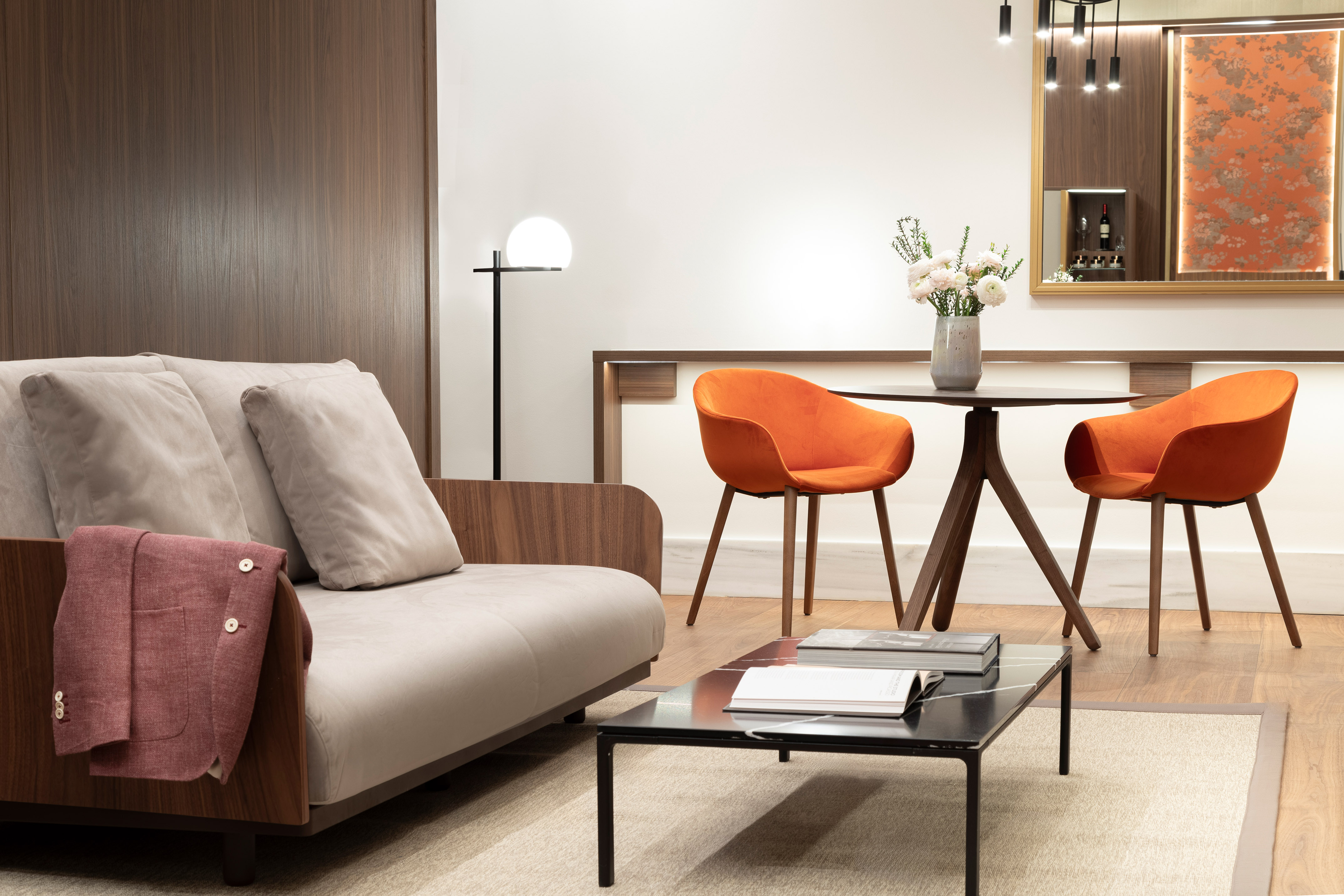 Modern lounge with beige sofa, orange chairs, coffee table, and elegant decor.