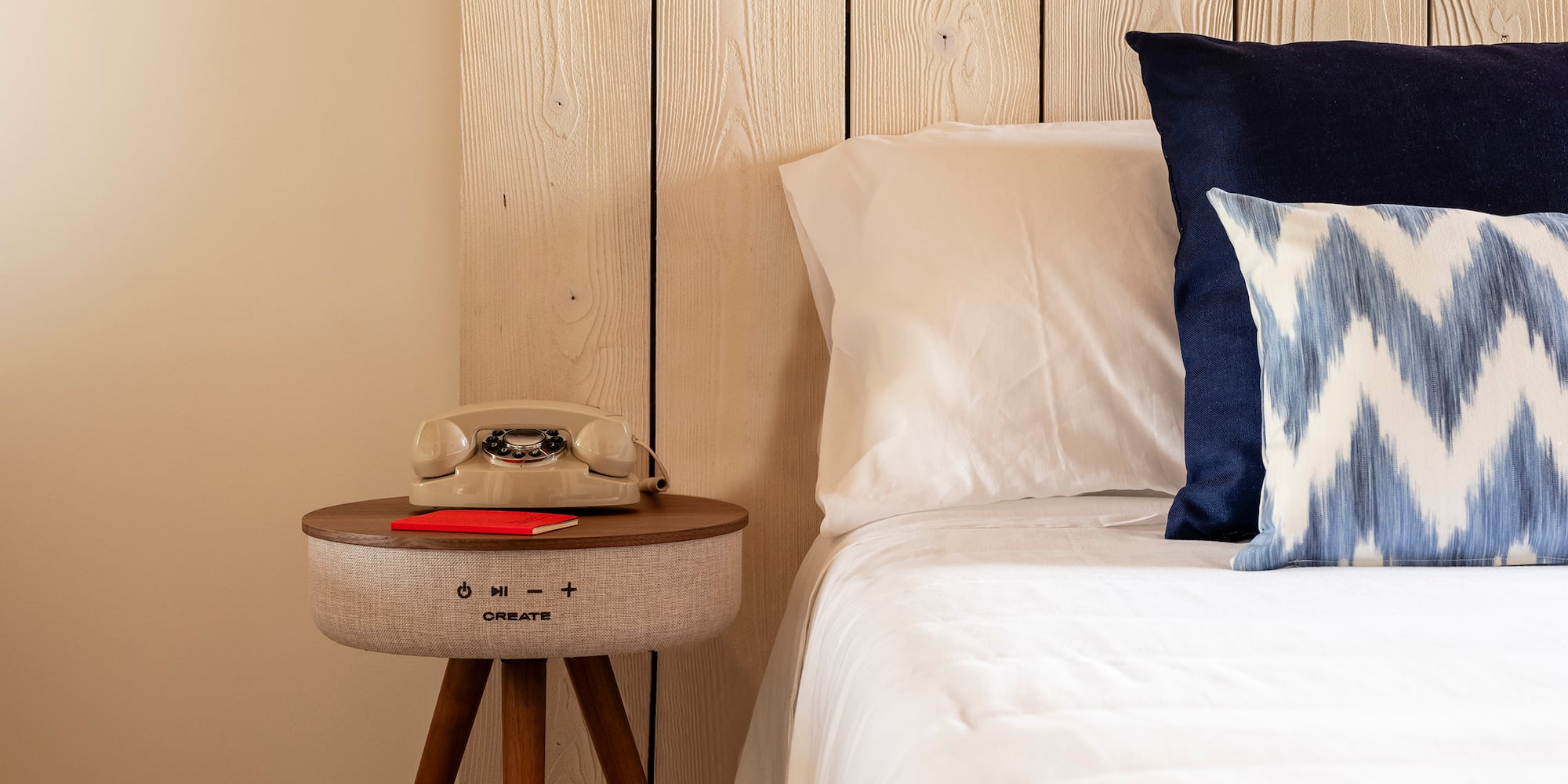 a bed with pillows and a telephone on a table