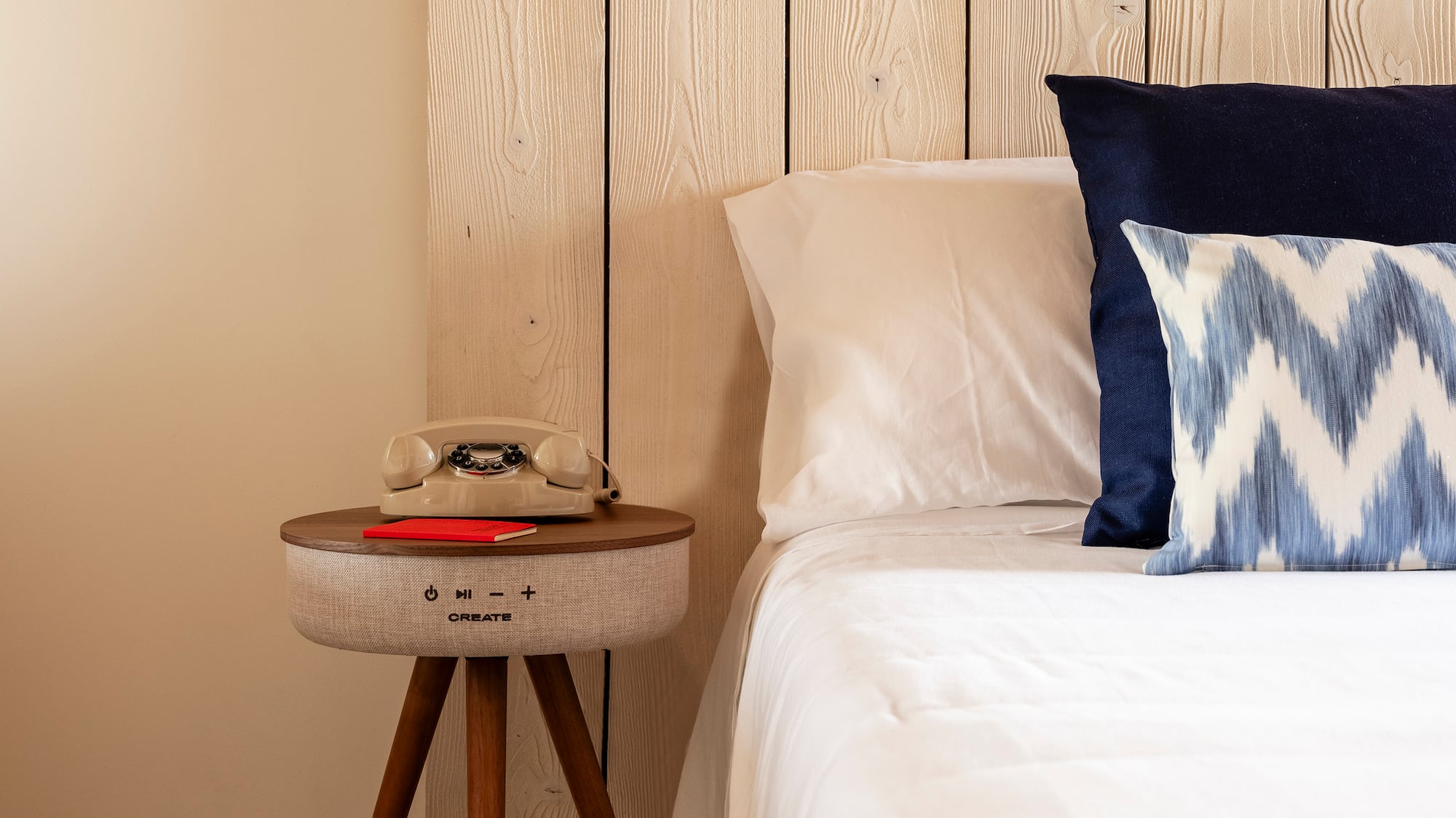 a bed with pillows and a telephone on a table