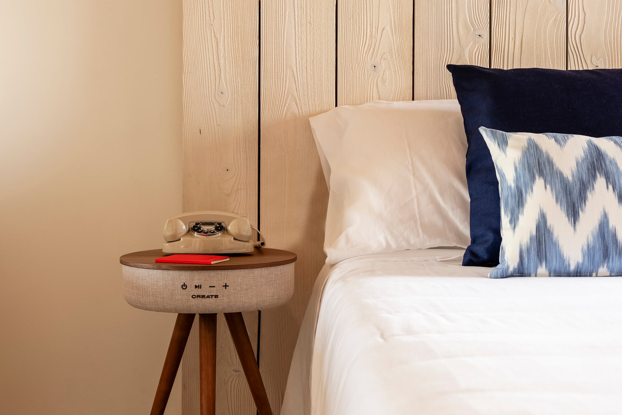 a bed with pillows and a telephone on a table