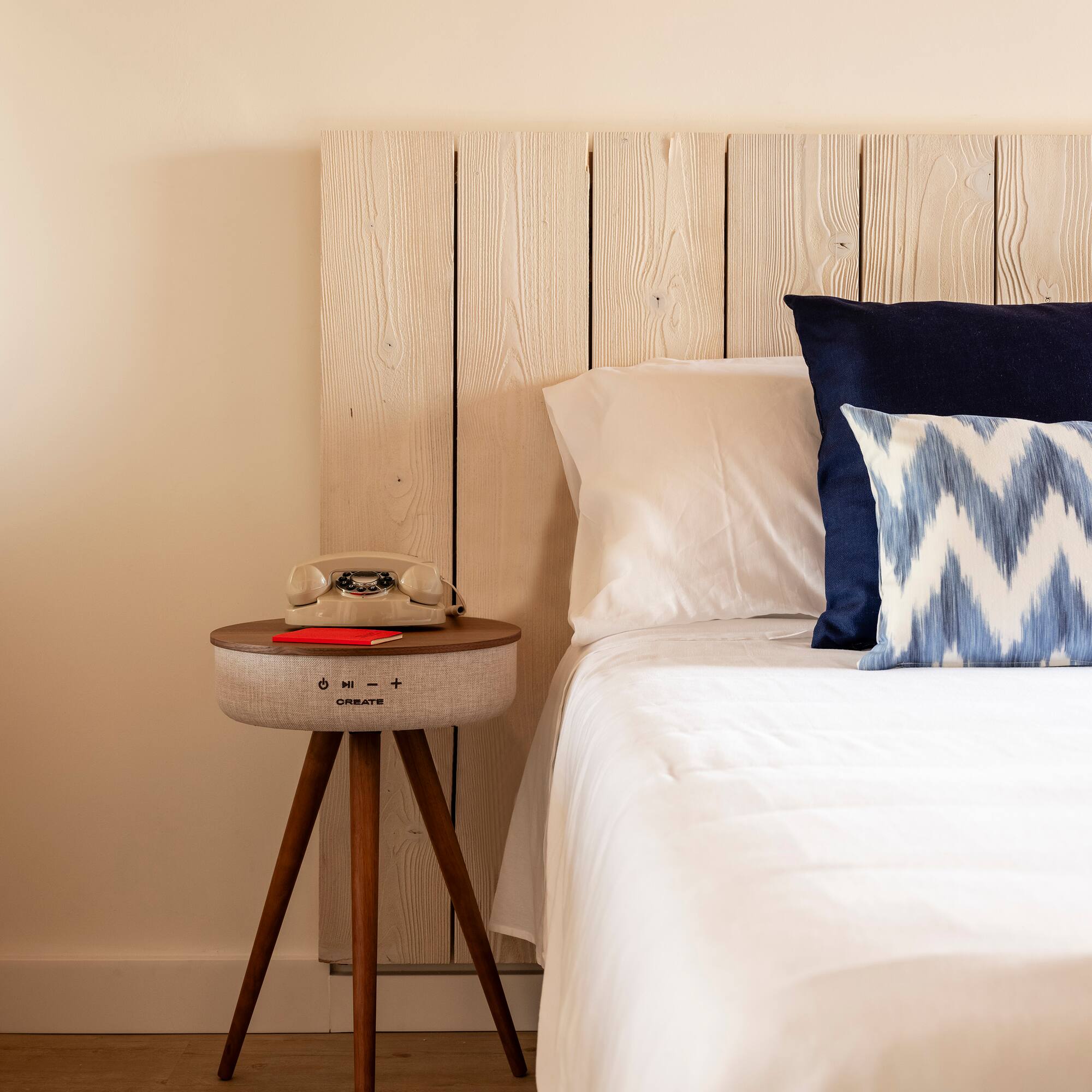 a bed with pillows and a telephone on a table