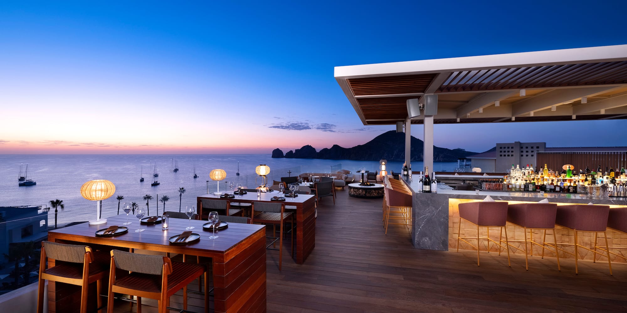 a restaurant with tables and chairs on a deck overlooking water