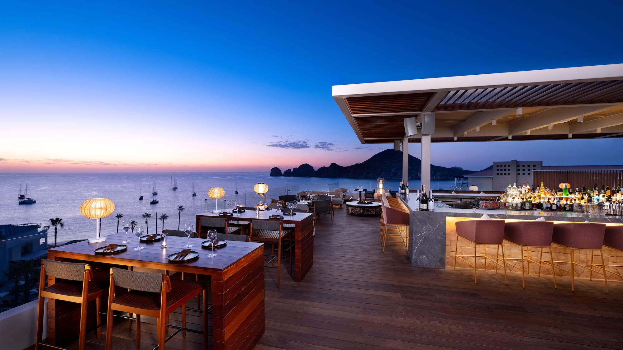 a restaurant with tables and chairs on a deck overlooking water