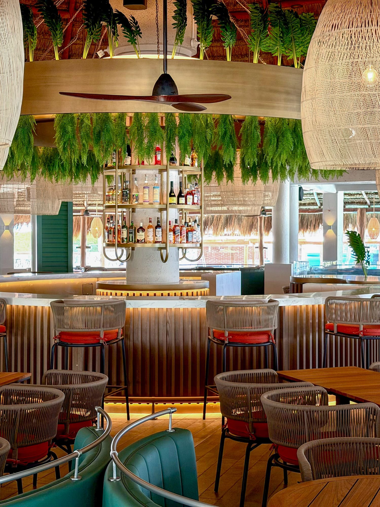 Lush tropical bar with woven pendant lights and modern dining seating.