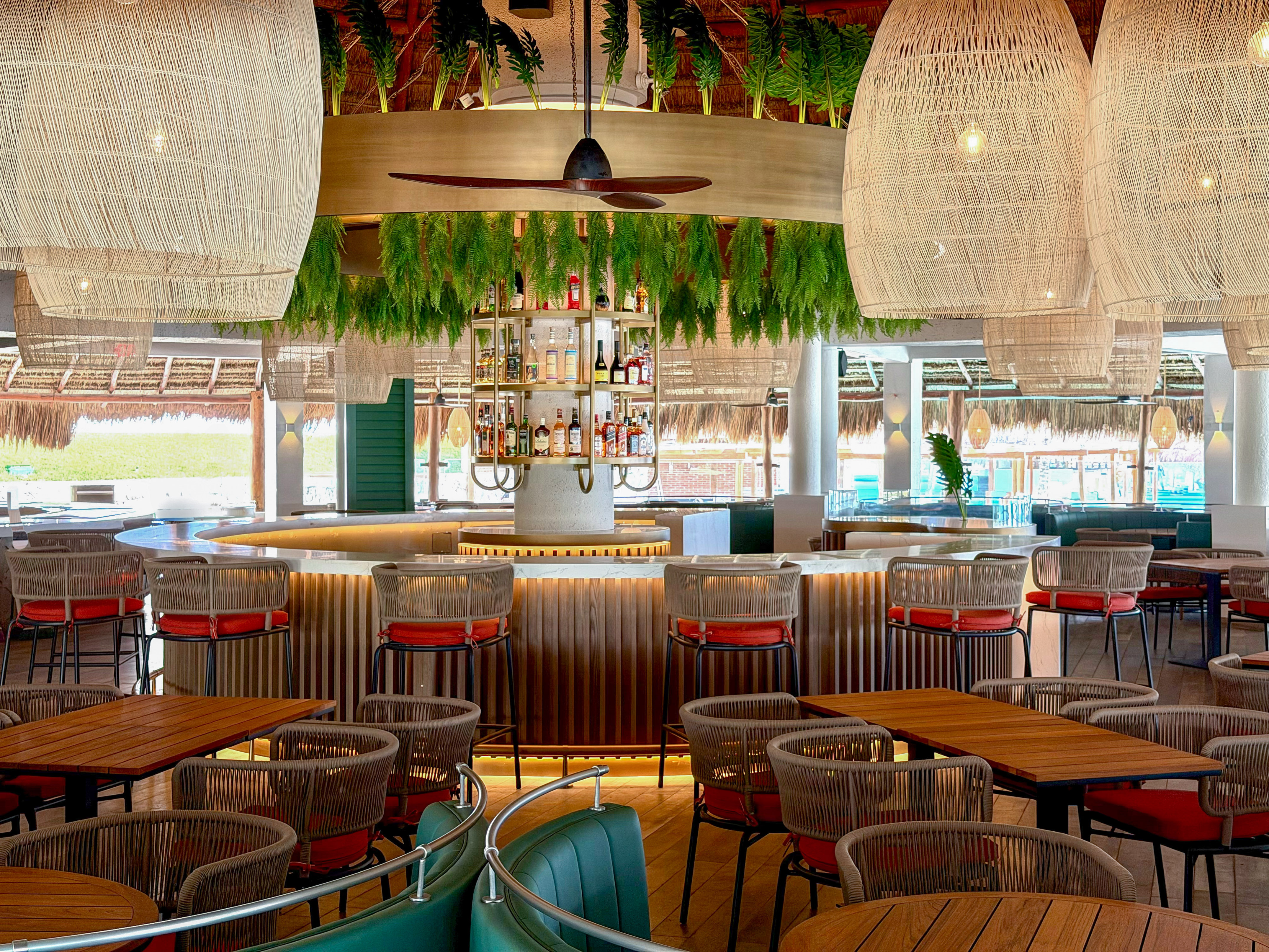 Lush tropical bar with woven pendant lights and modern dining seating.