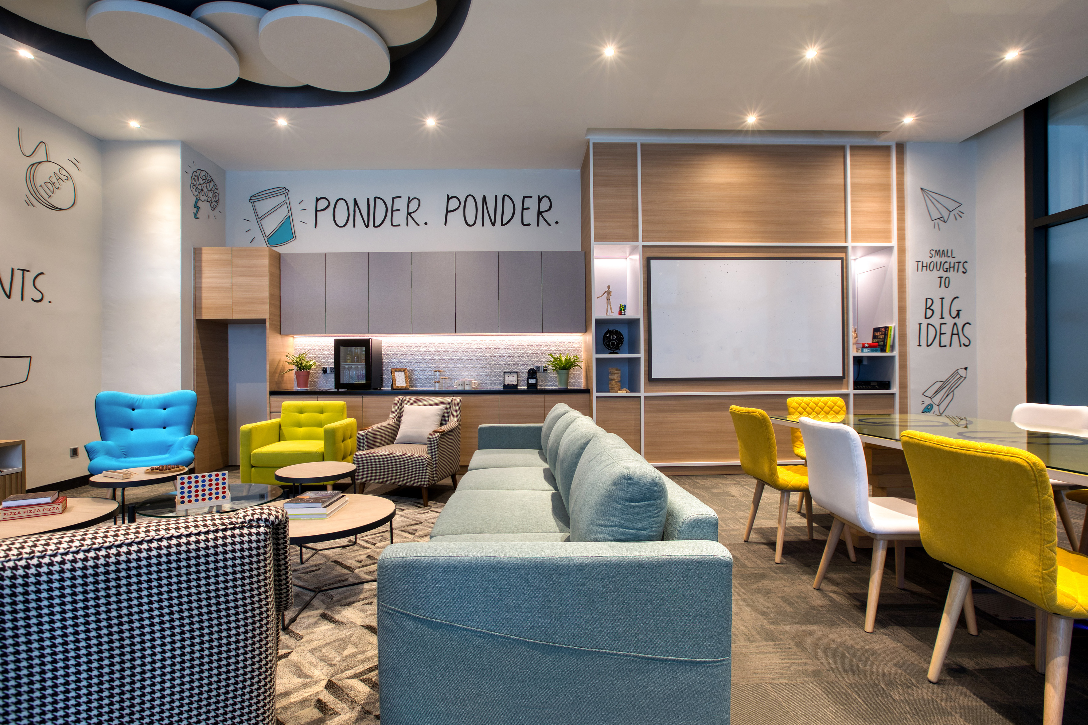 Colorful modern office lounge with seating, coffee bar, and creative PONDER wall.
