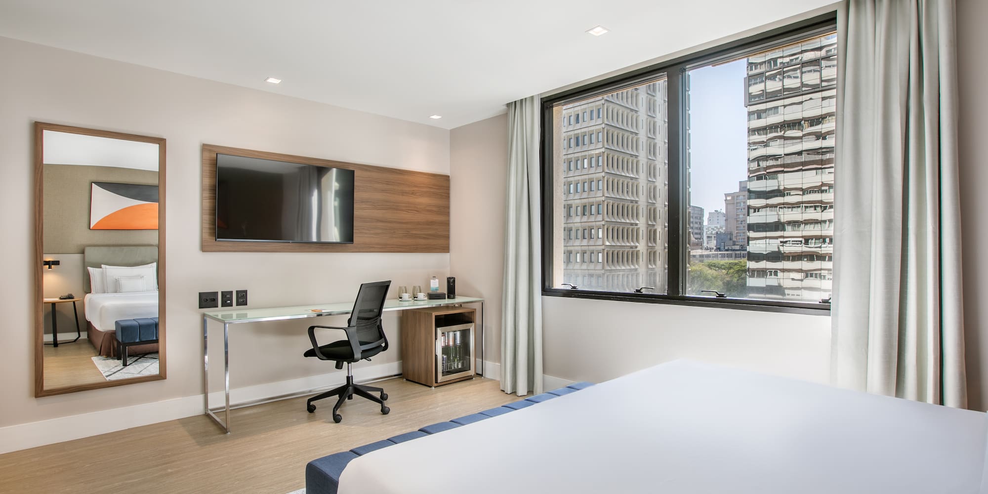 a room with a bed and a desk and a television