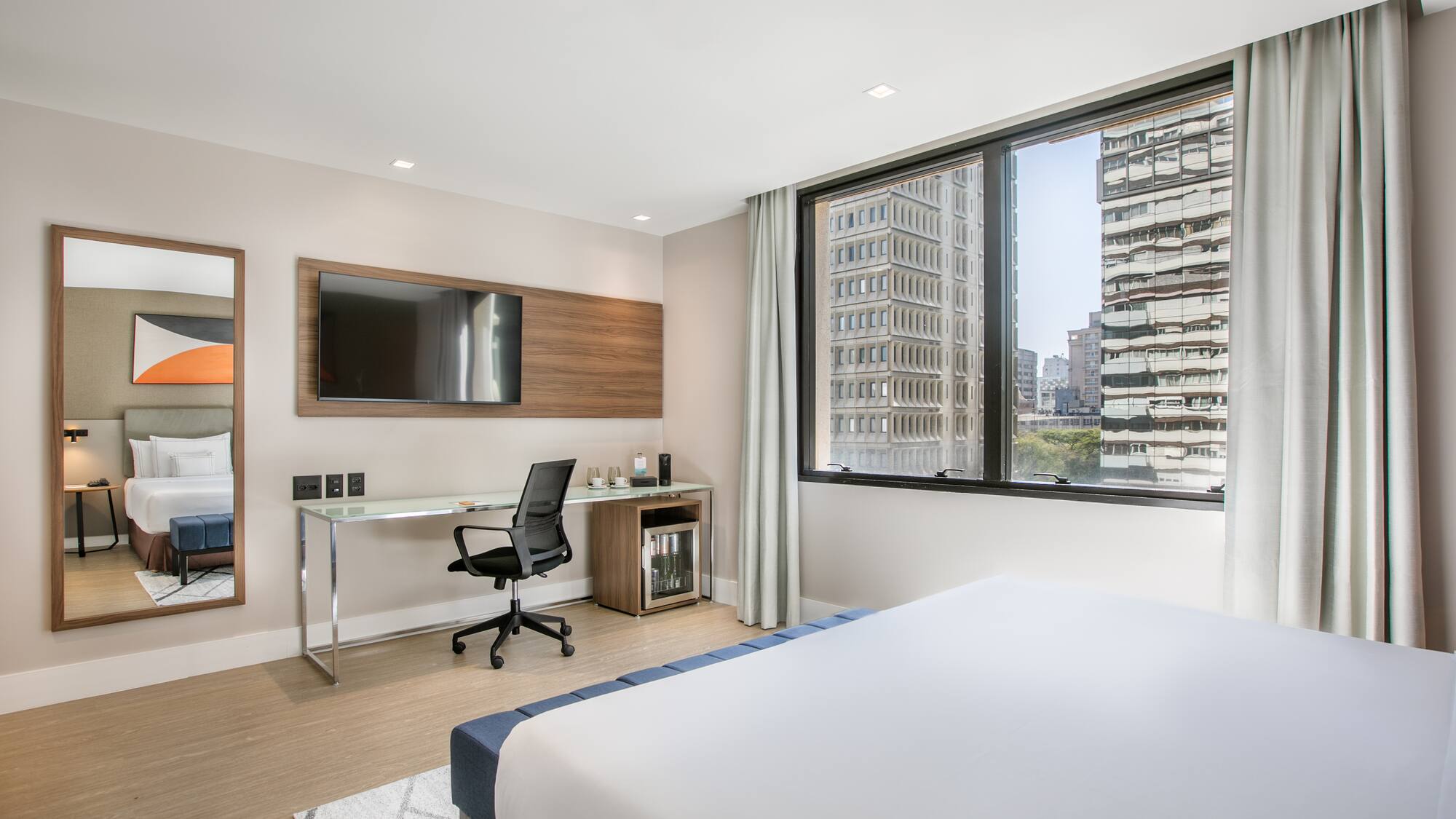 a room with a bed and a desk and a television