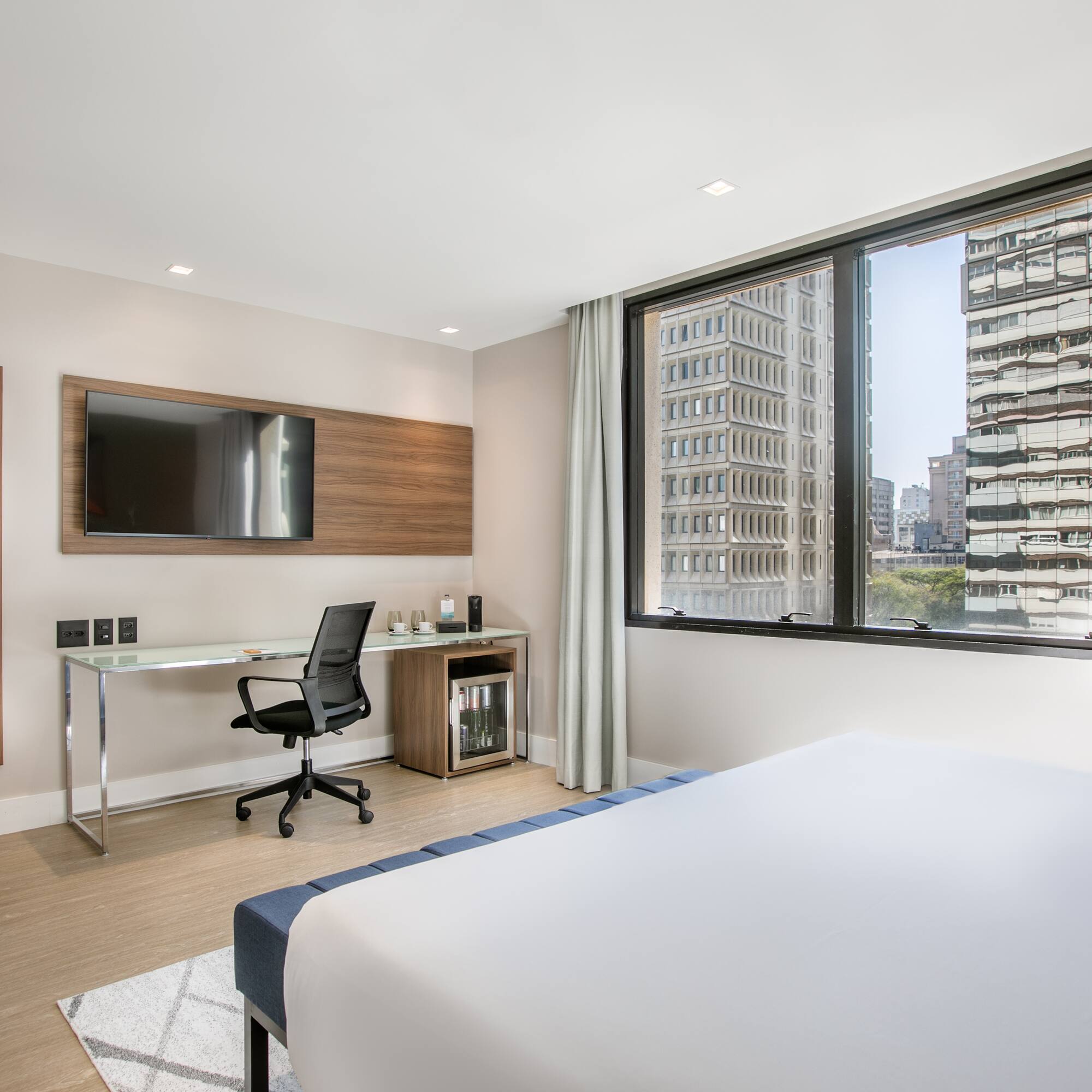 a room with a bed and a desk and a television