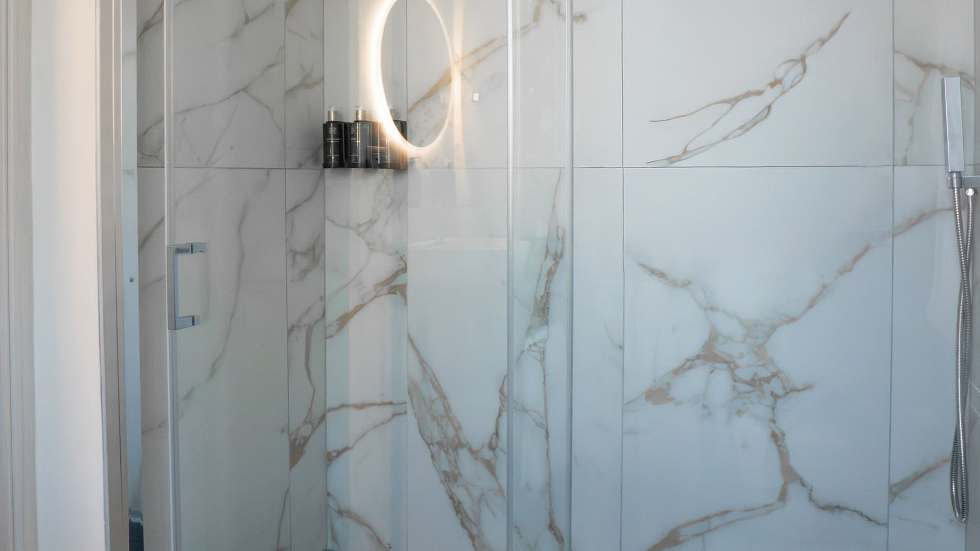 a glass shower with a round mirror