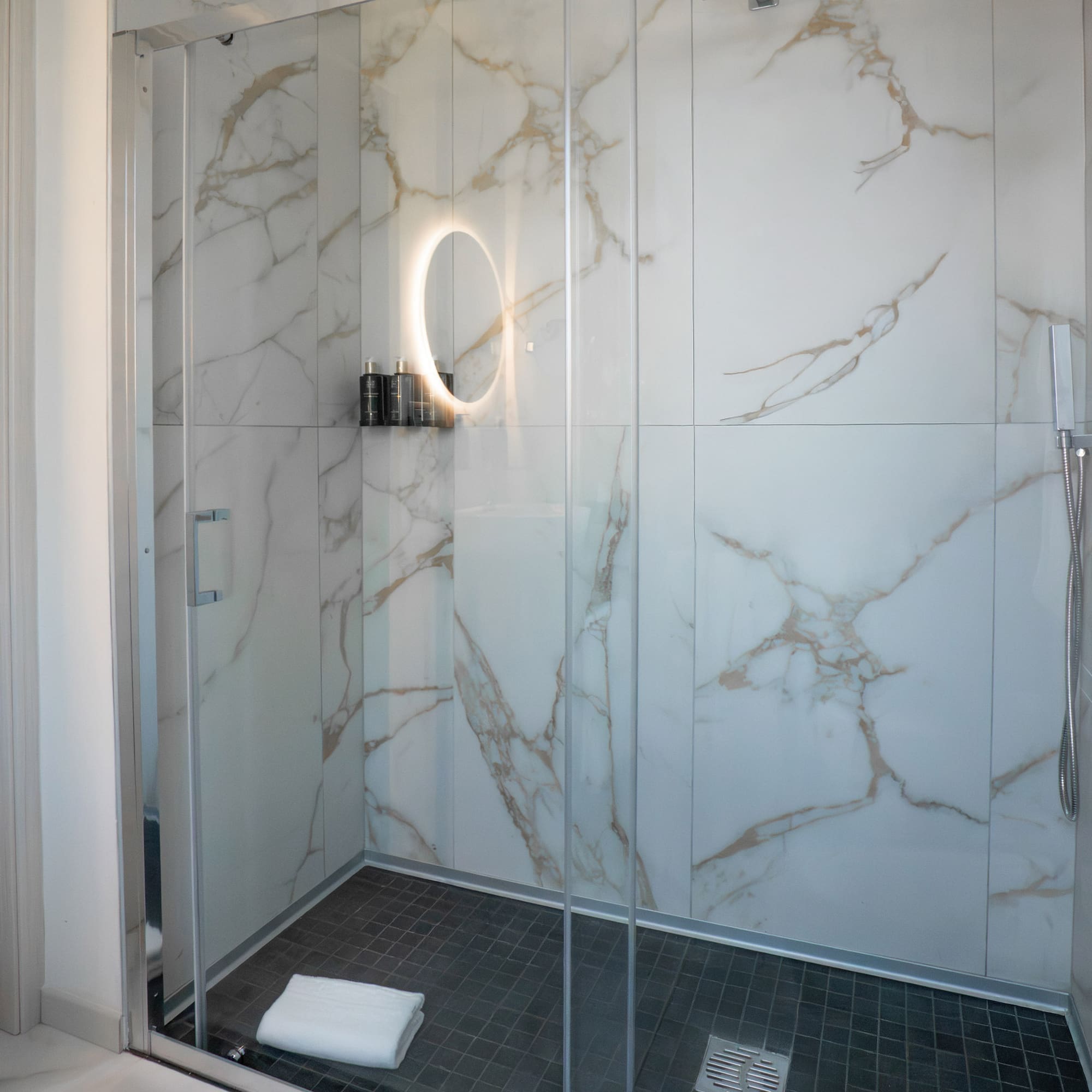 a glass shower with a round mirror