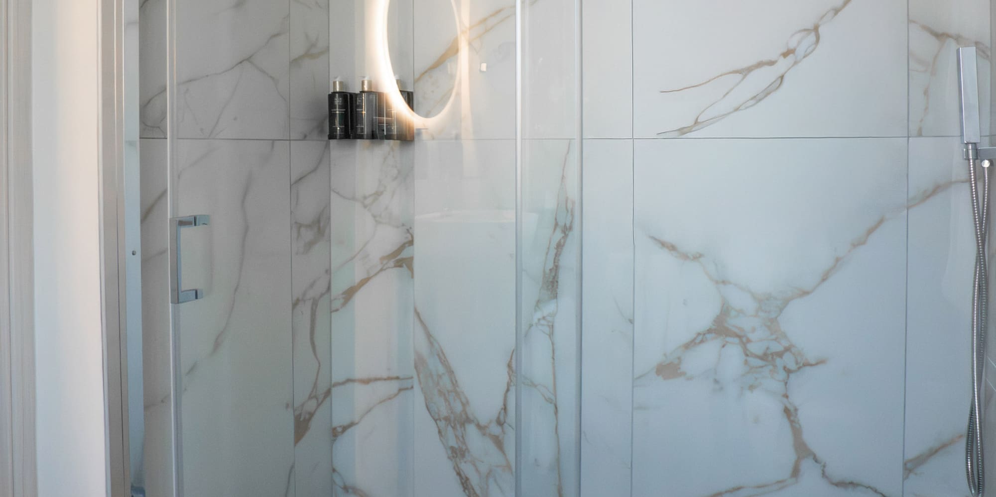 a glass shower with a round mirror