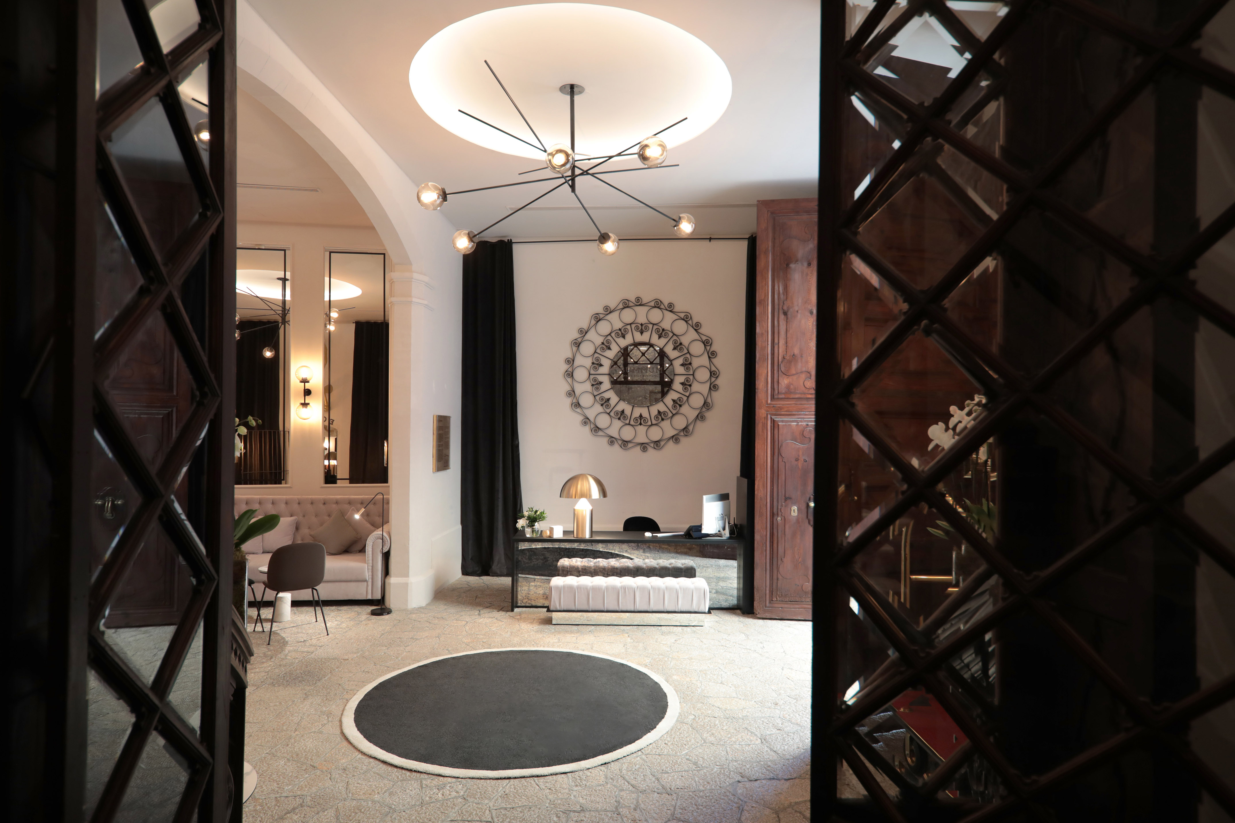 Hotel lobby with modern chandelier, elegant reception desk, and lounge seating.