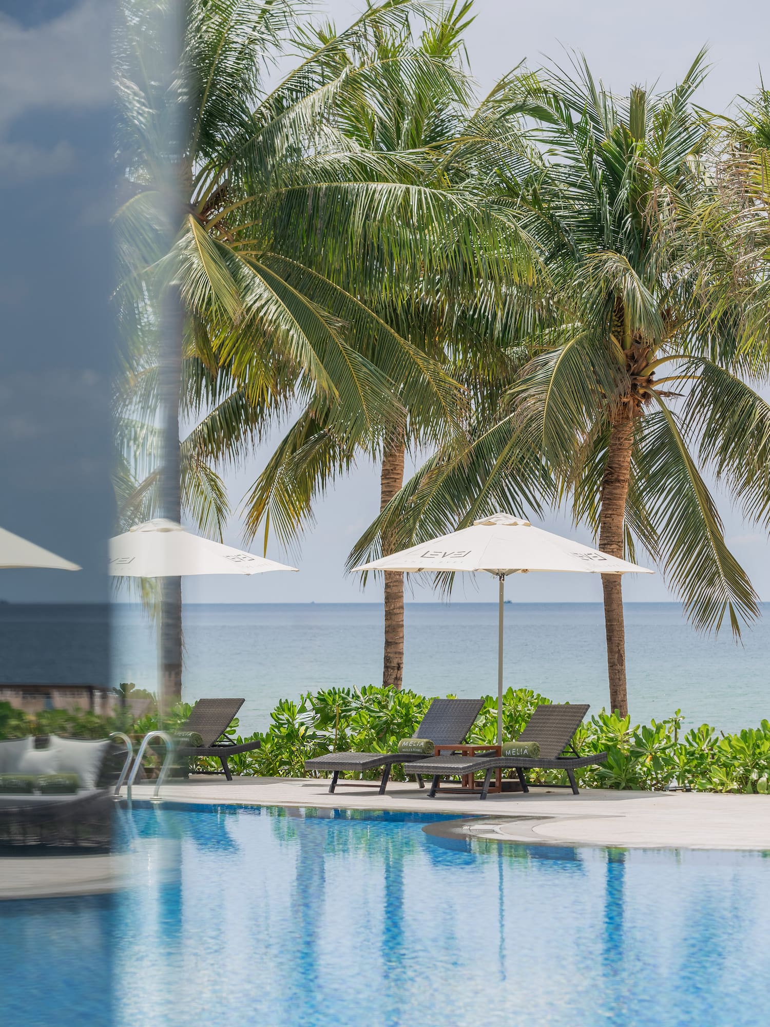 a pool with umbrellas and chairs by the water