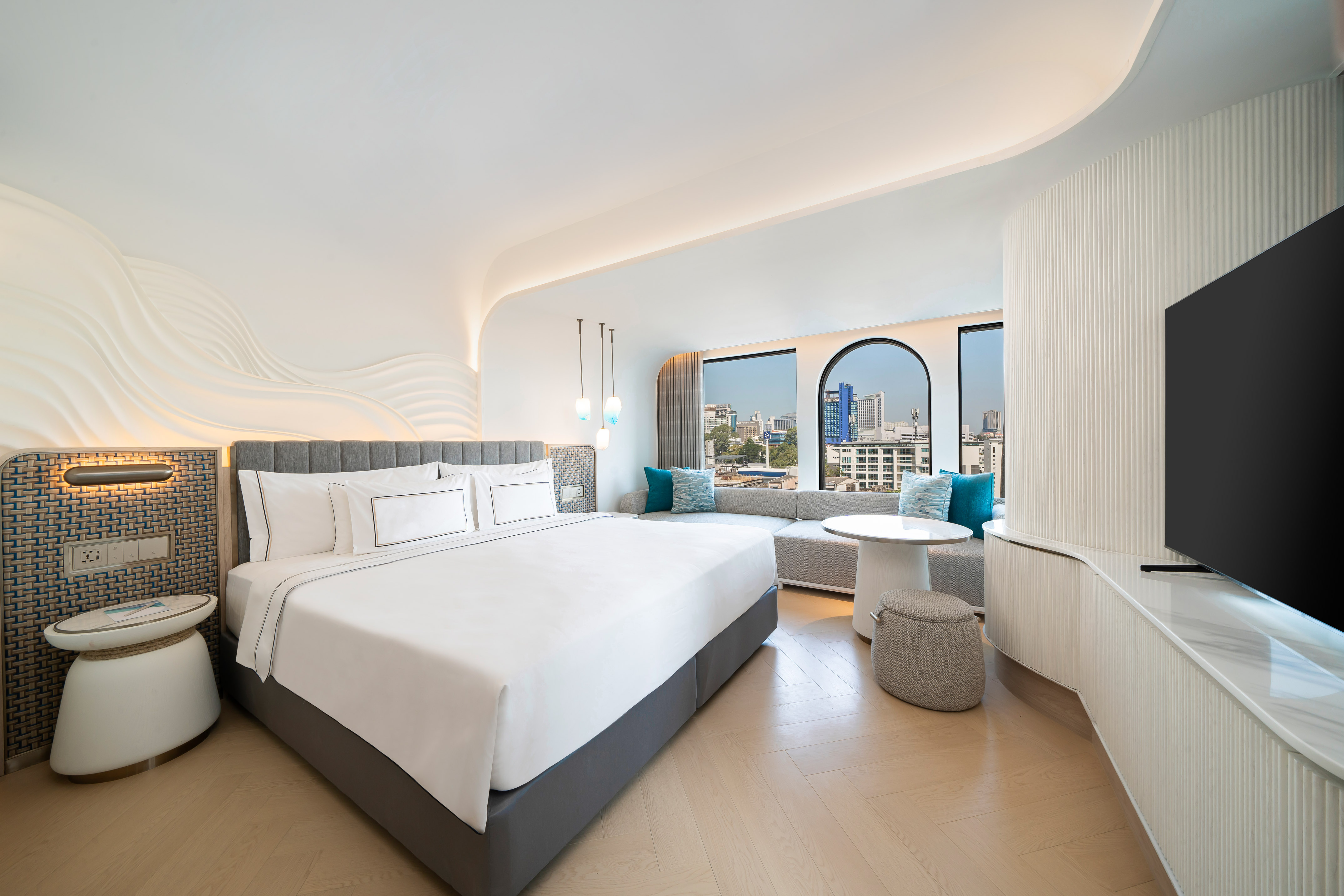 Bright modern hotel room with city view, king bed, and stylish decor.