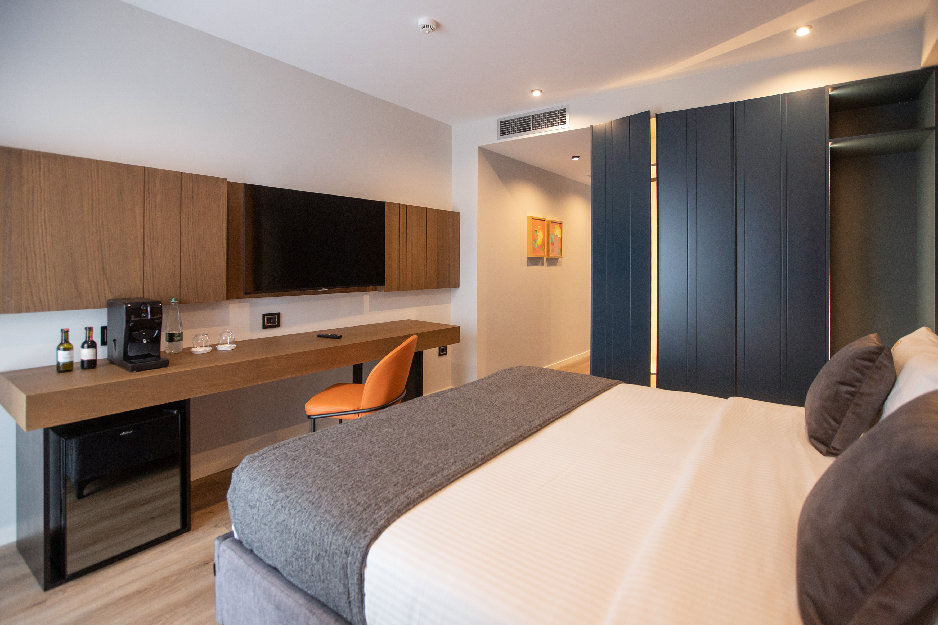 Contemporary hotel room with large bed, TV, desk, and built-in closet.