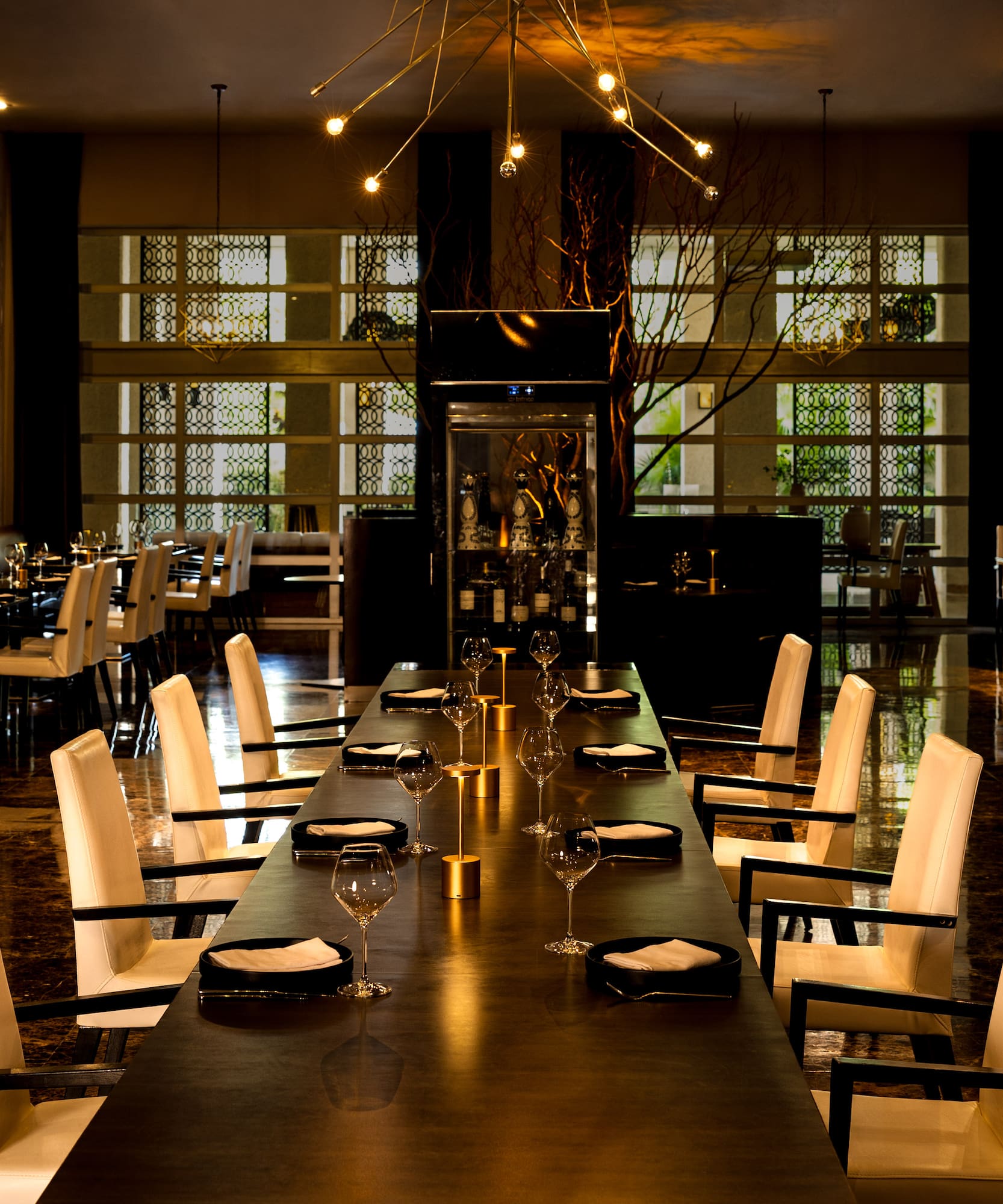 Elegant dining room, long table, white chairs, modern chandeliers.