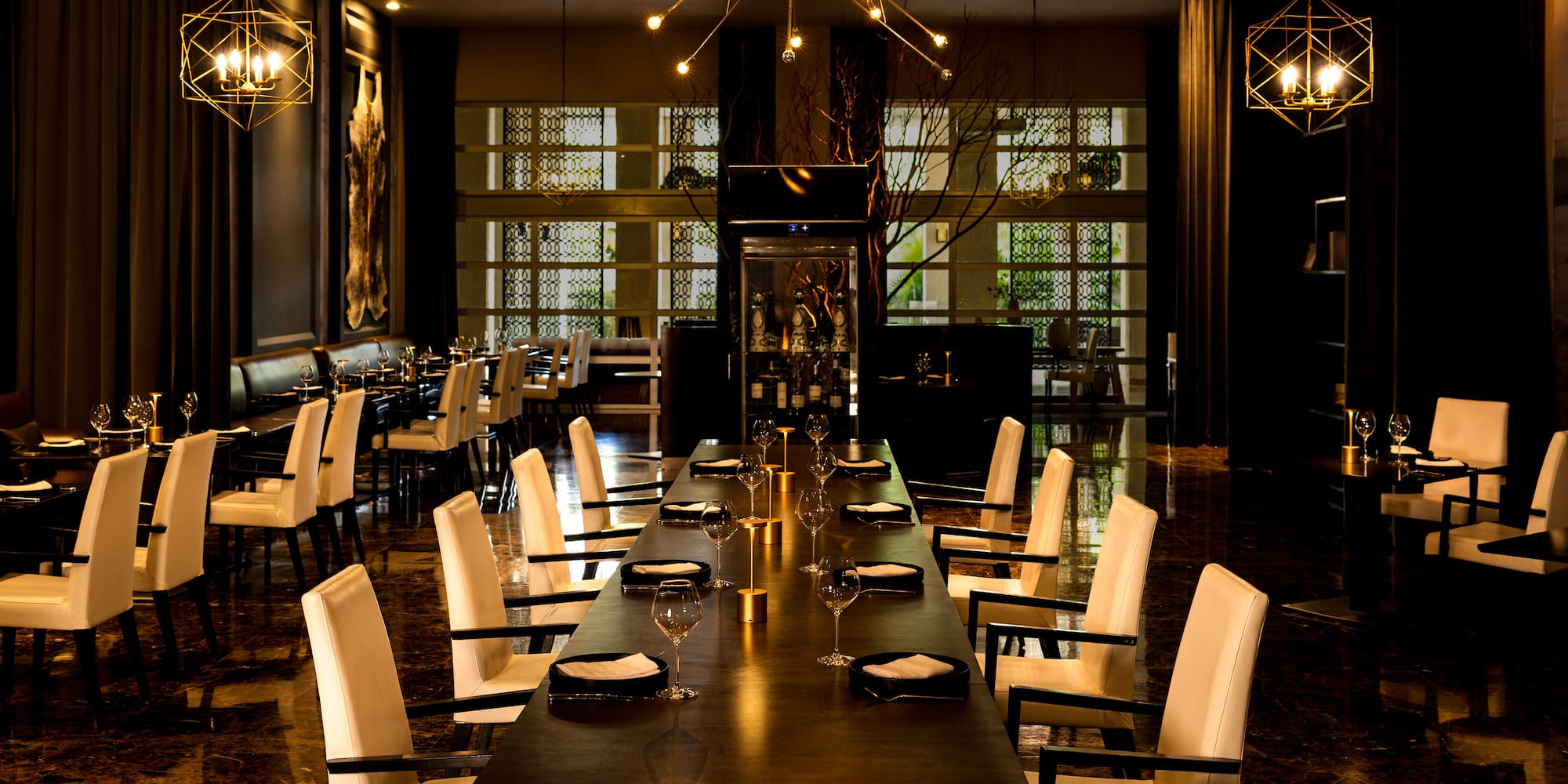 Elegant dining room, long table, white chairs, modern chandeliers.