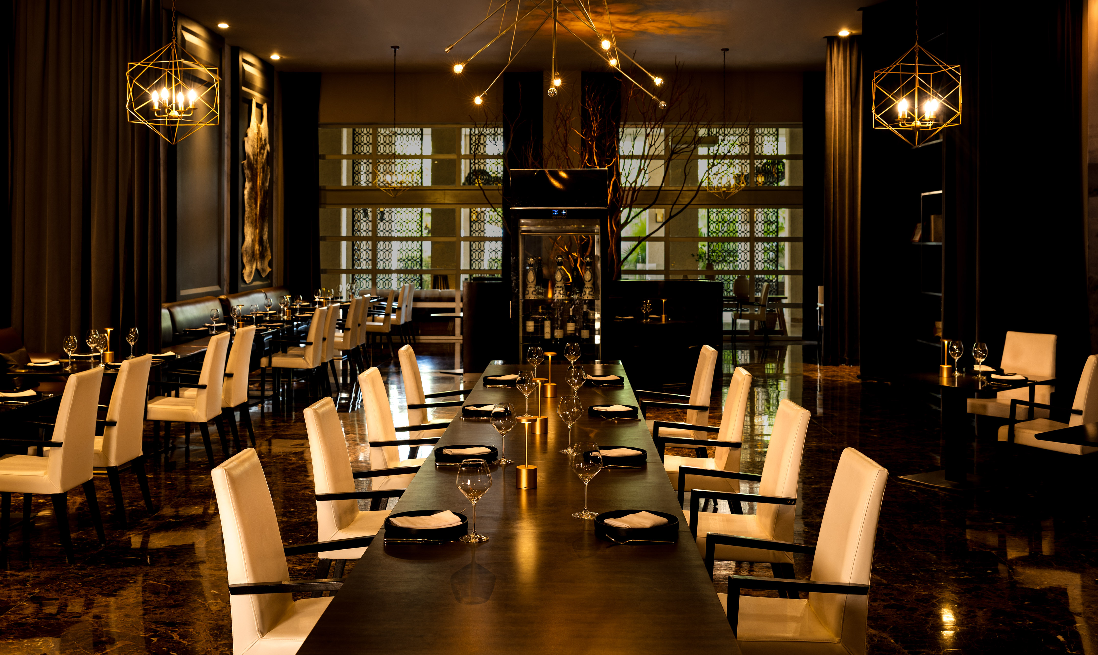 Elegant dining room, long table, white chairs, modern chandeliers.