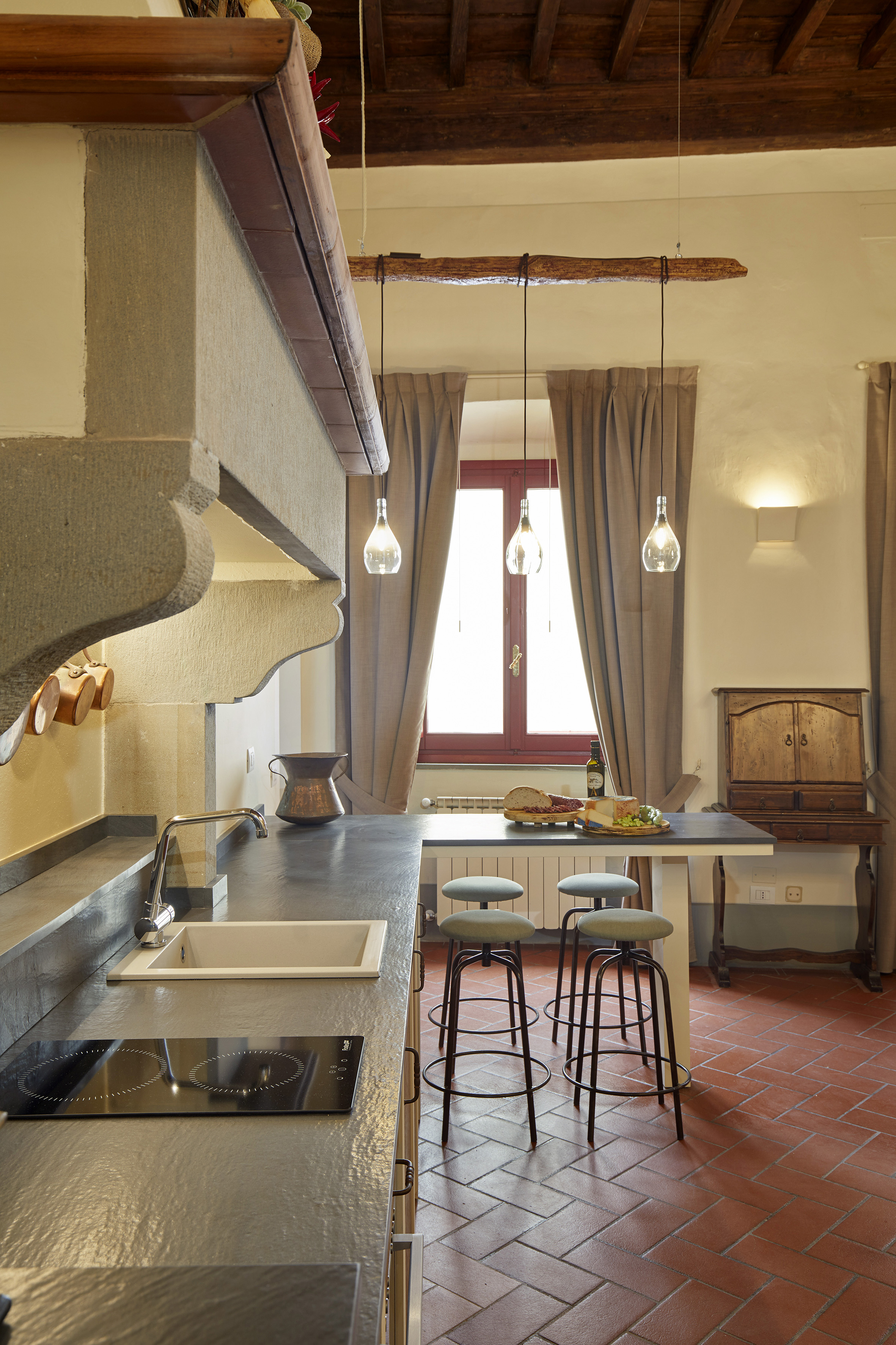 Rustic kitchen: stone counters, terracotta floor, induction hob, dining island.