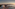 Aerial view: Modern coastal resort hotel, beach, and sunrise over ocean.