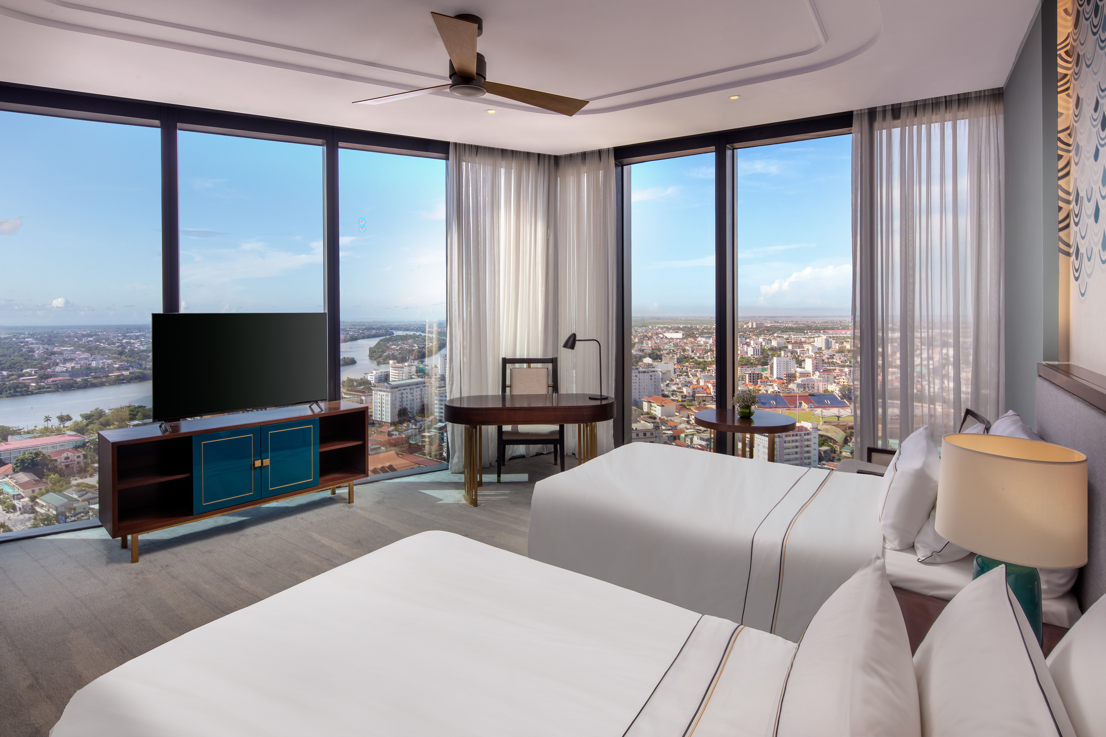 Luxury hotel room with two beds, panoramic city and river views.