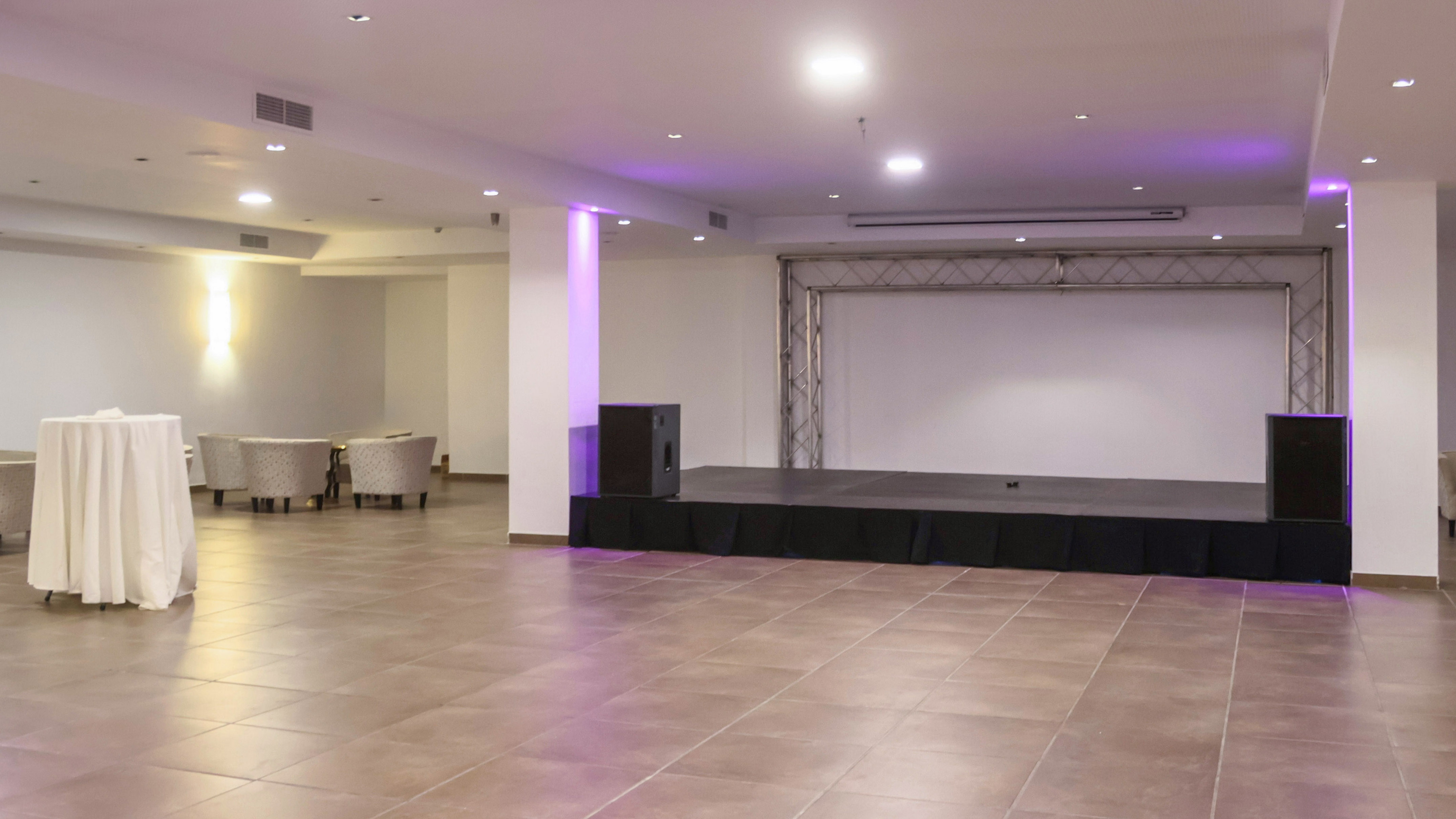 Modern event hall with stage, sound system, screen, and lounge seating.