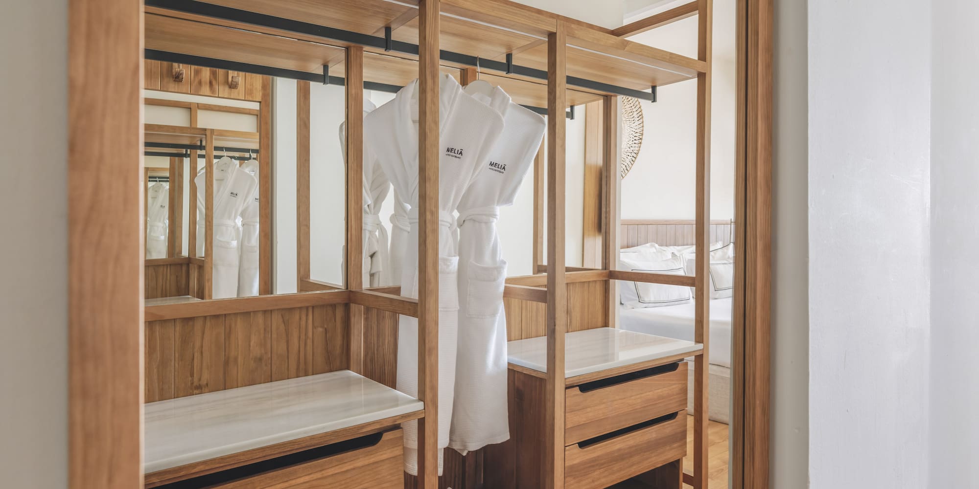 Meliã hotel room: open wooden wardrobe with white bathrobes, slippers, drawers.