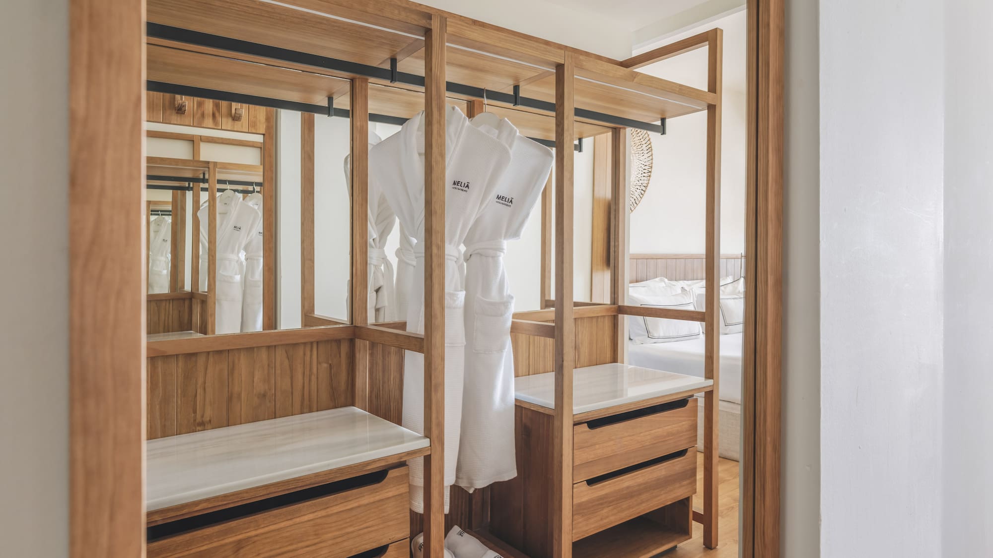 Meliã hotel room: open wooden wardrobe with white bathrobes, slippers, drawers.