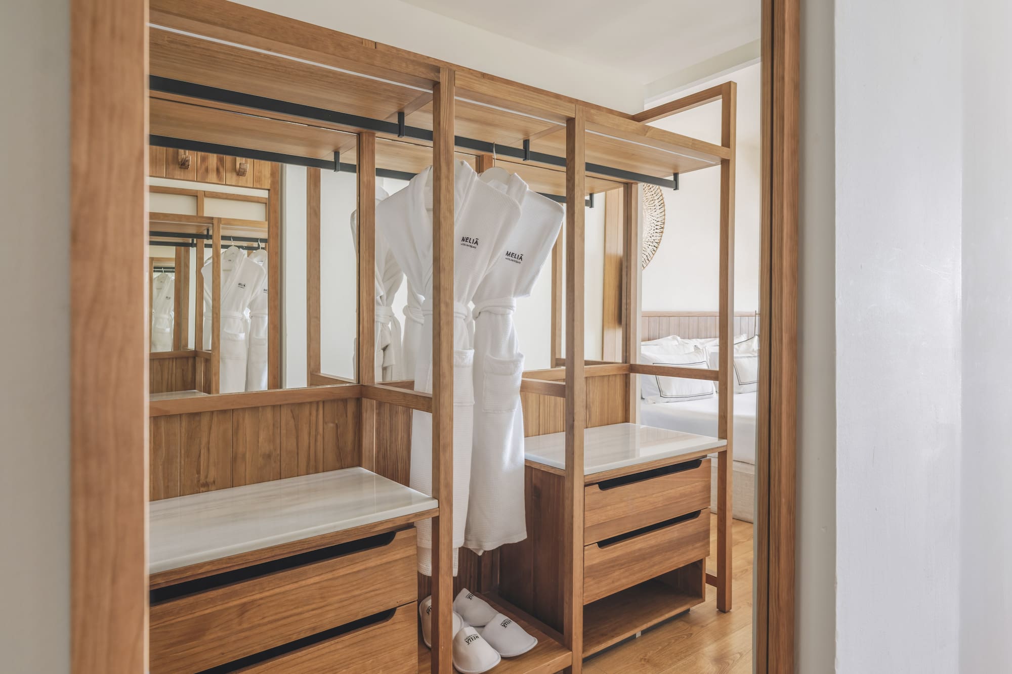 Meliã hotel room: open wooden wardrobe with white bathrobes, slippers, drawers.