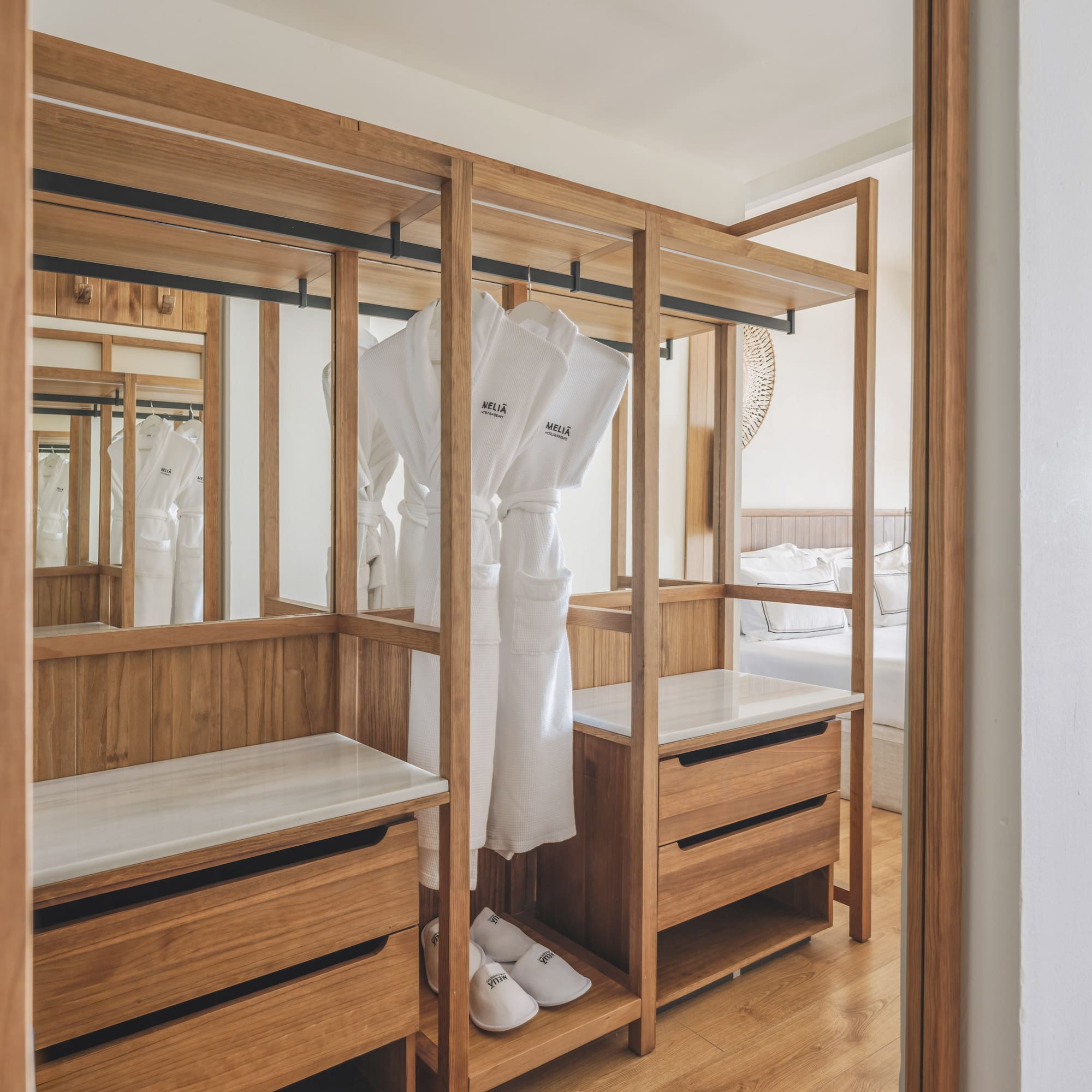 Meliã hotel room: open wooden wardrobe with white bathrobes, slippers, drawers.