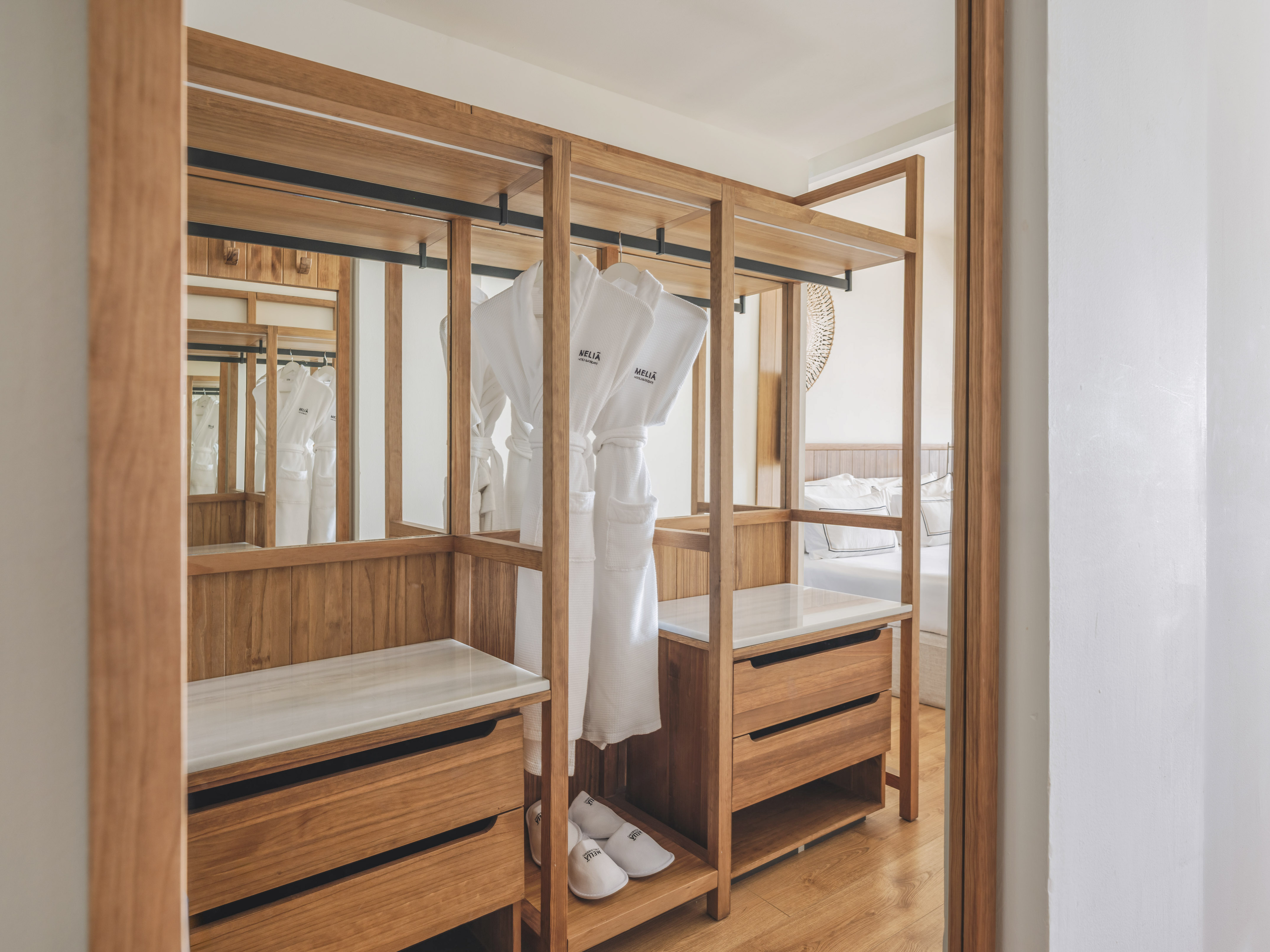 Meliã hotel room: open wooden wardrobe with white bathrobes, slippers, drawers.