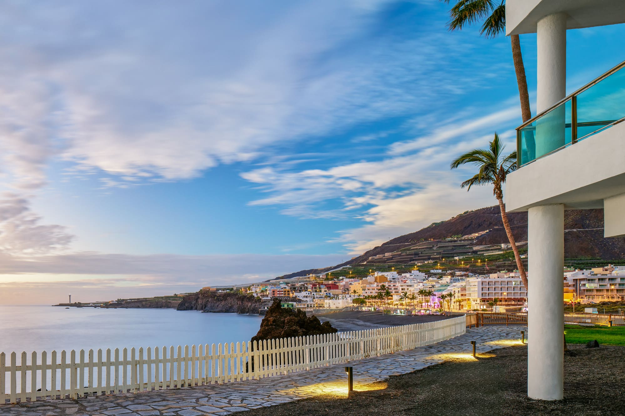Sunset over Tazacorte, La Palma coastal town with ocean, lighthouse, and resort.