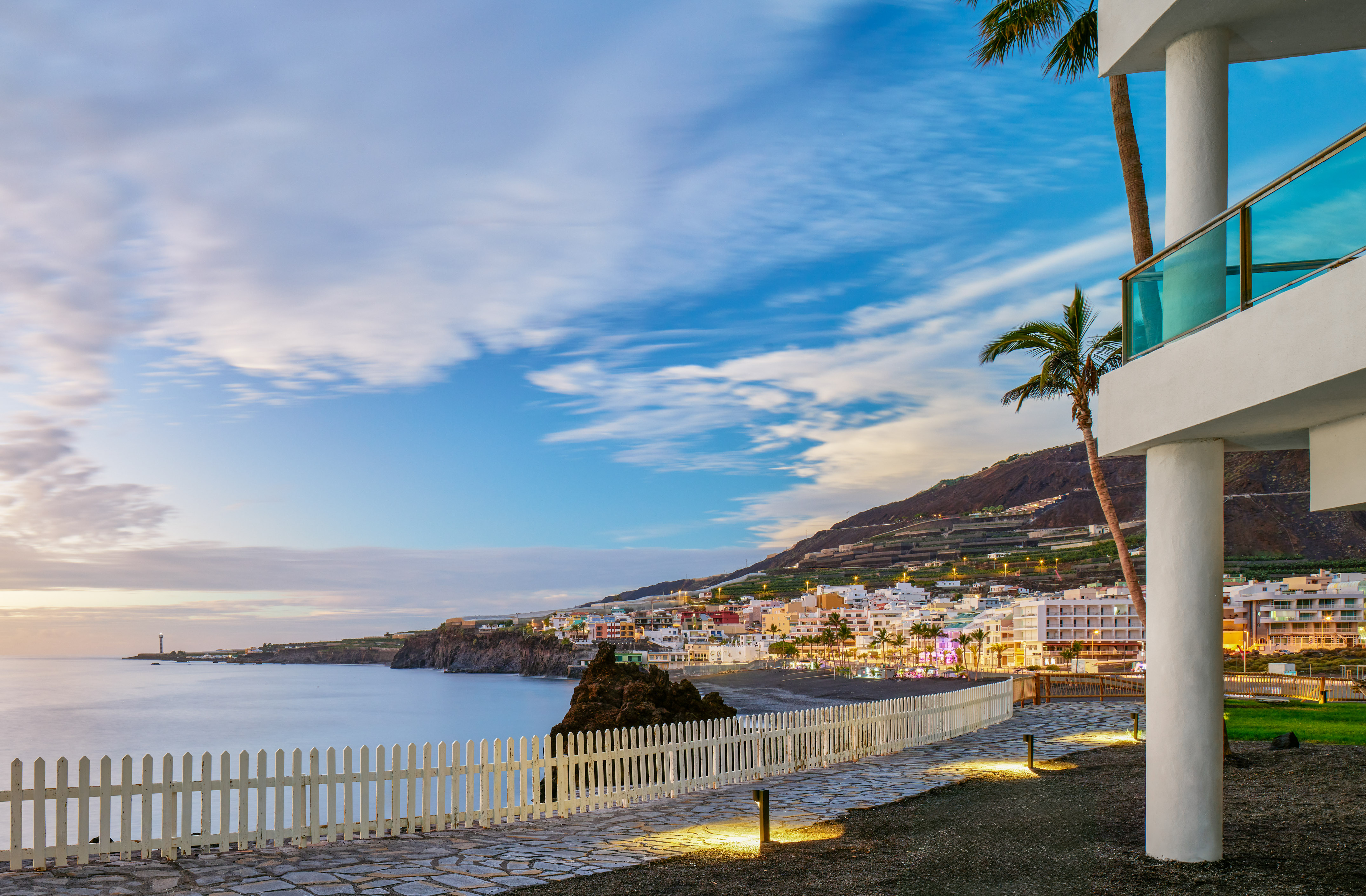 Sunset over Tazacorte, La Palma coastal town with ocean, lighthouse, and resort.